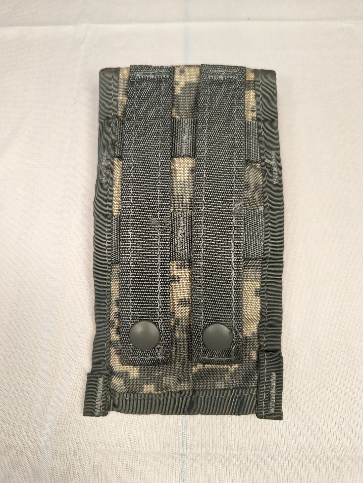 A U.S. Military Surplus Double Magazine Pouch in ACU digital camouflage, viewed from the front, featuring two vertical webbing straps with black snap button closures, displayed on a white background.