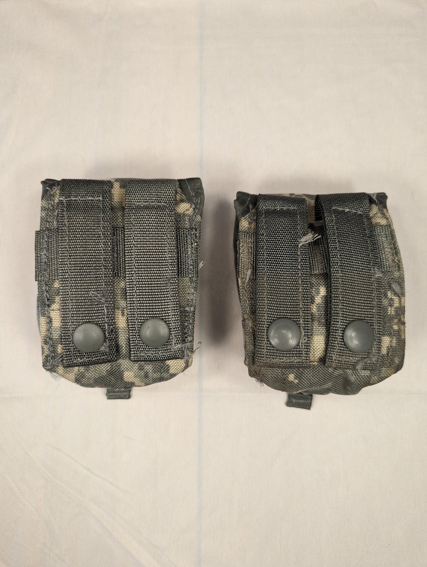 A close-up studio shot of two U.S. Military Surplus Double Magazine Pouches in ACU digital camouflage, laid side-by-side, featuring dense horizontal MOLLE webbing and snap-button flaps.
