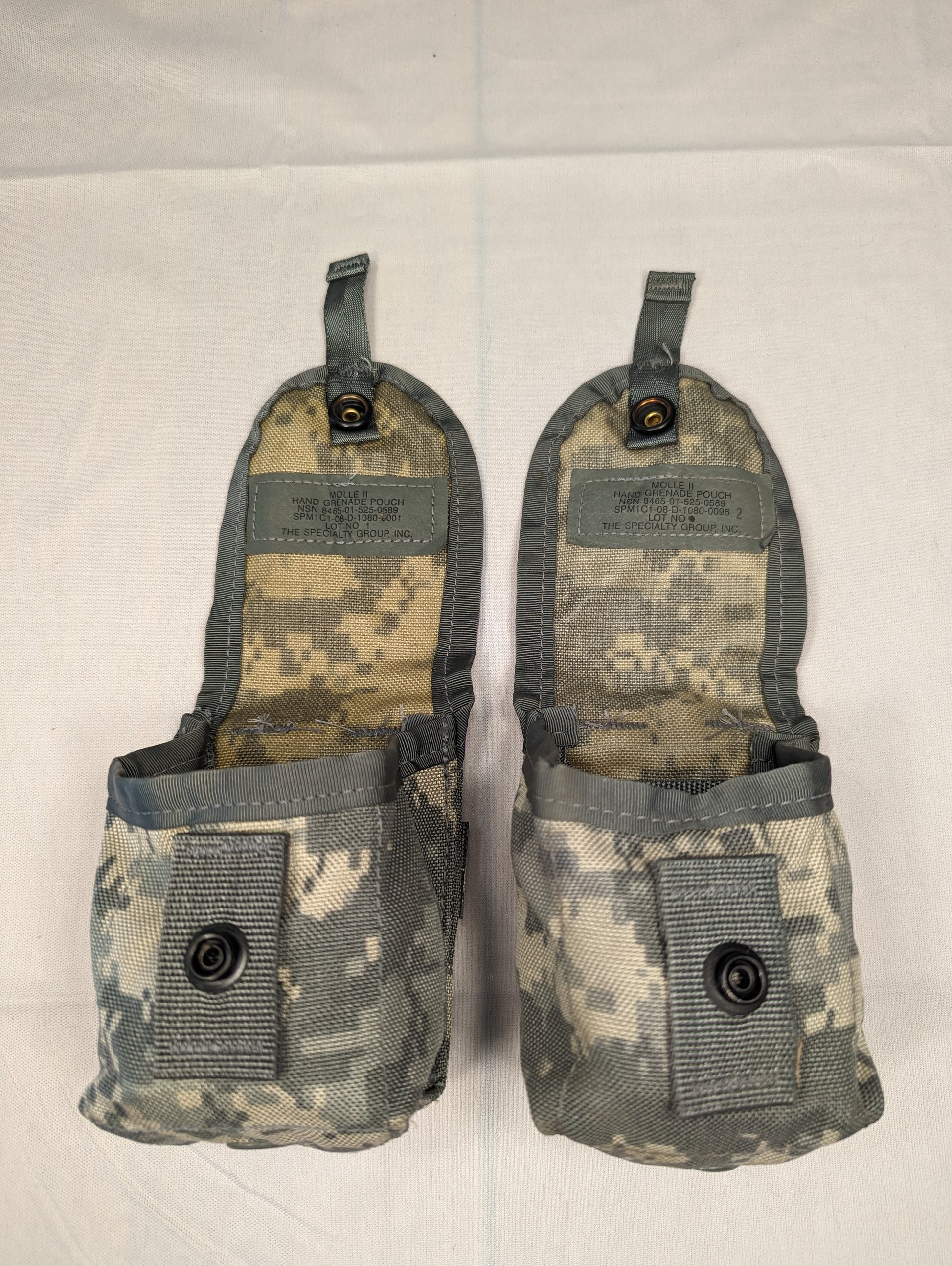 A studio shot of two U.S. Military Surplus Hand Grenade Pouches in ACU digital camouflage, shown side-by-side with their top flaps open, revealing the empty interiors and issue markings.