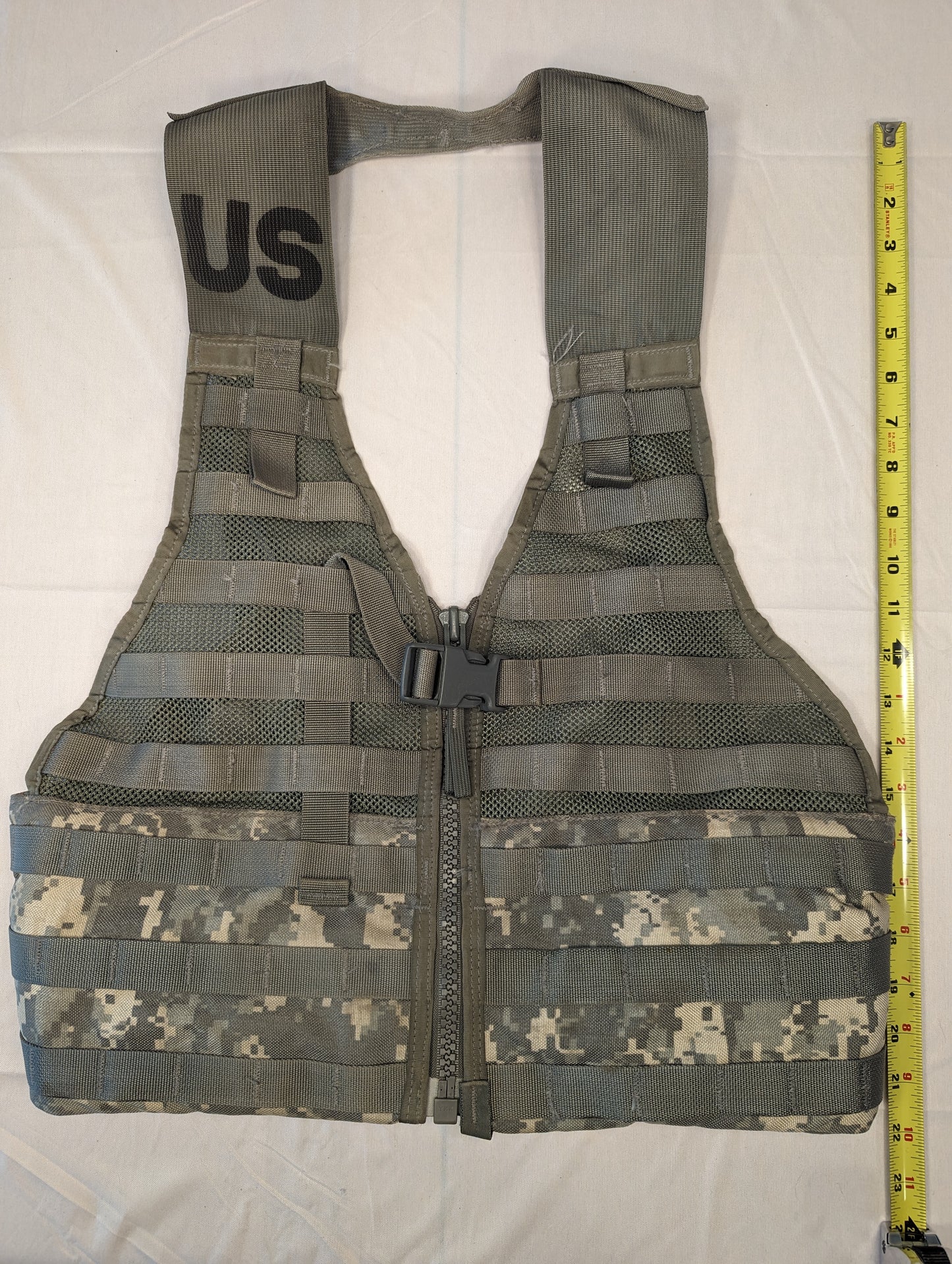 A full front view of a U.S. Military Surplus Load Carrier Vest (FLC) in ACU digital camouflage, unaccessorized, laid flat with a tape measure showing its vertical height, highlighting the extensive MOLLE webbing.
