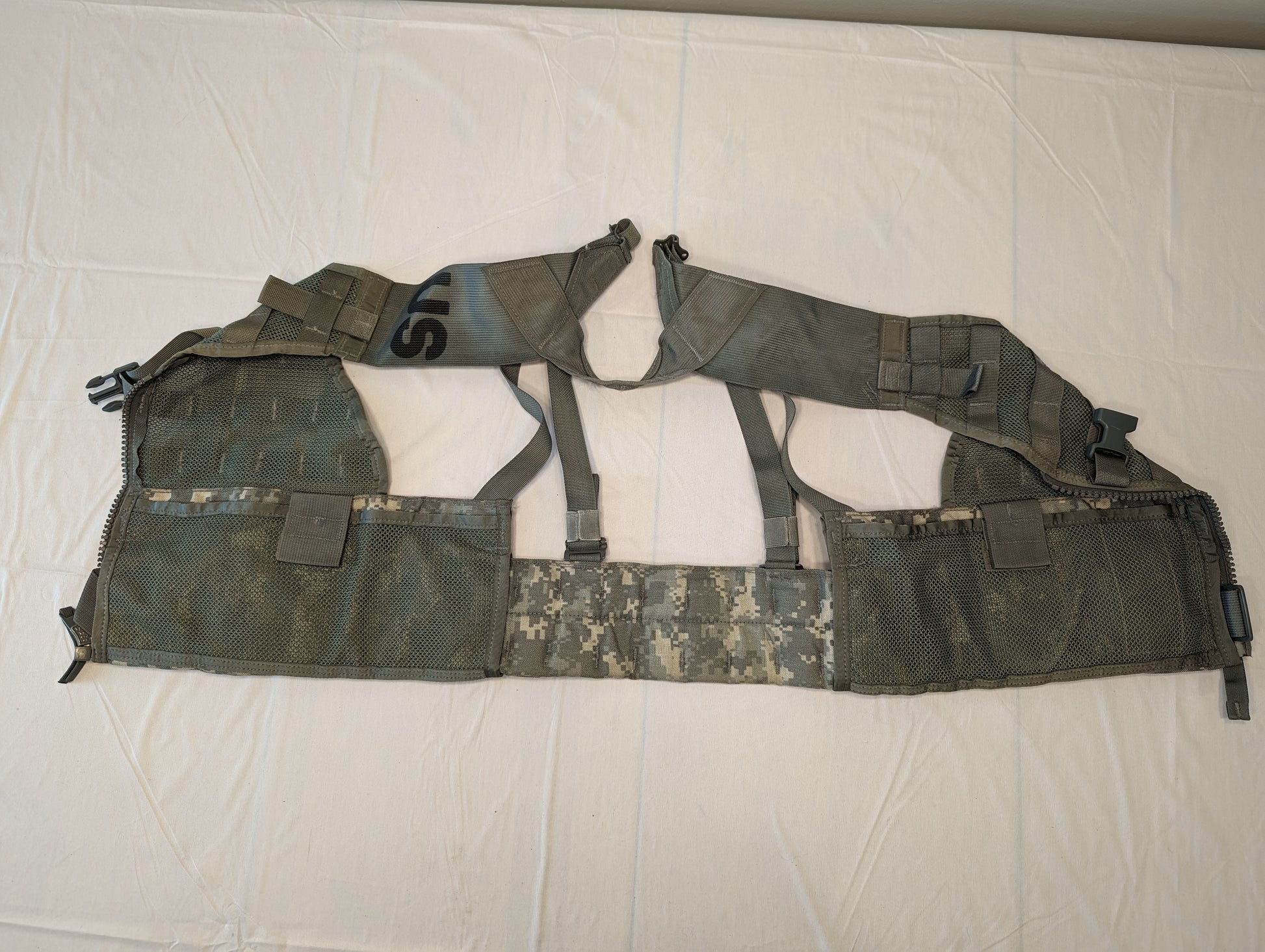 An overhead view of a U.S. Military Surplus Load Carrier Vest (FLC) in ACU digital camouflage, laid flat and open to display the inner mesh lining, front zipper track, and the extensive horizontal MOLLE webbing.