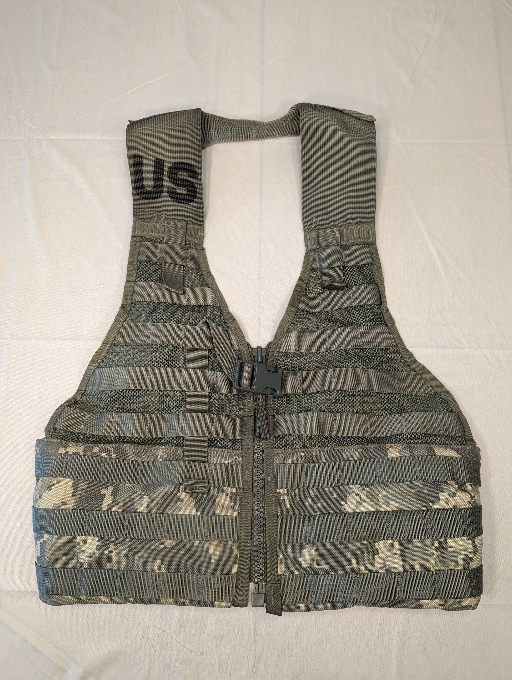 A full front view of a U.S. Military Surplus Load Carrier Vest (FLC) in ACU digital camouflage, unaccessorized, displaying the extensive horizontal MOLLE webbing and the 'U.S.' government marking on the shoulder.