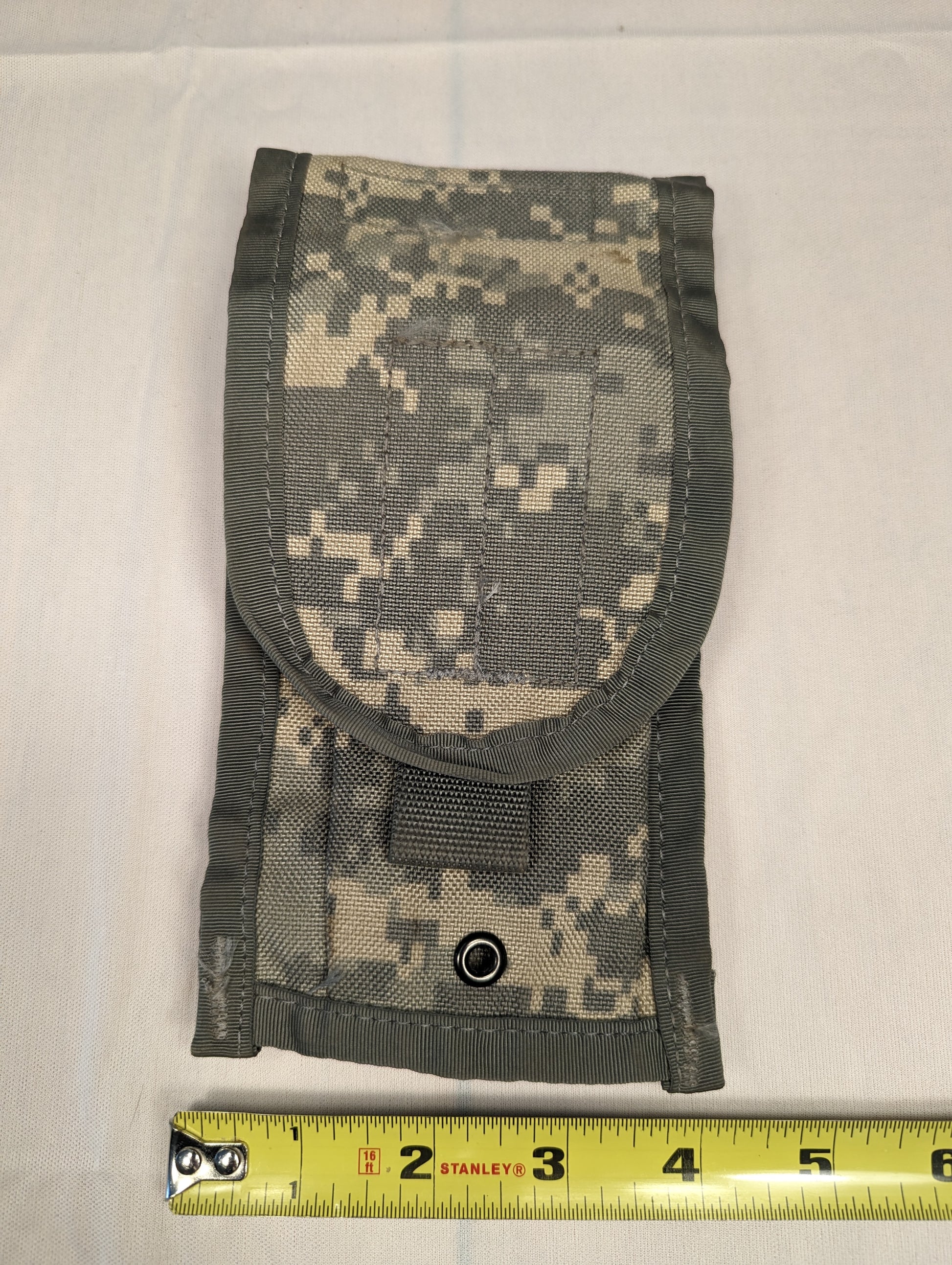 A single U.S. Military Surplus Pouch in ACU digital camouflage, laid flat, featuring a rounded top flap, a securing strap with hook-and-loop closure, and a tape measure demonstrating its width of approximately 5 inches.