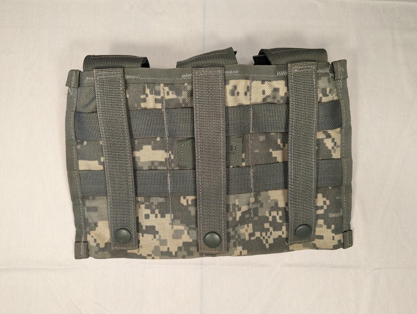 A close-up overhead view of a single U.S. Military Surplus Triple Magazine Pouch in ACU digital camouflage, displaying the dense horizontal MOLLE webbing and three visible snap buttons.