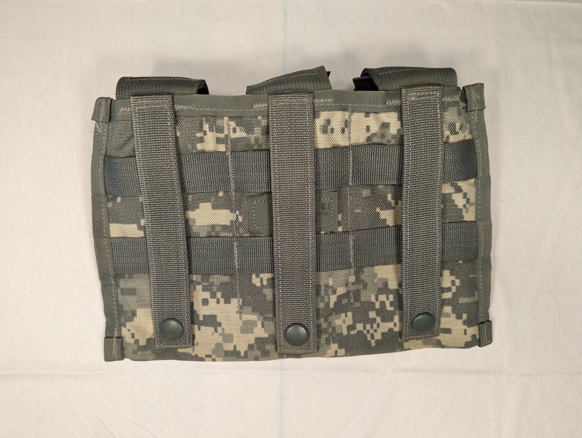 A close-up overhead view of a single U.S. Military Surplus Triple Magazine Pouch in ACU digital camouflage, displaying the dense horizontal MOLLE webbing and three visible snap buttons.