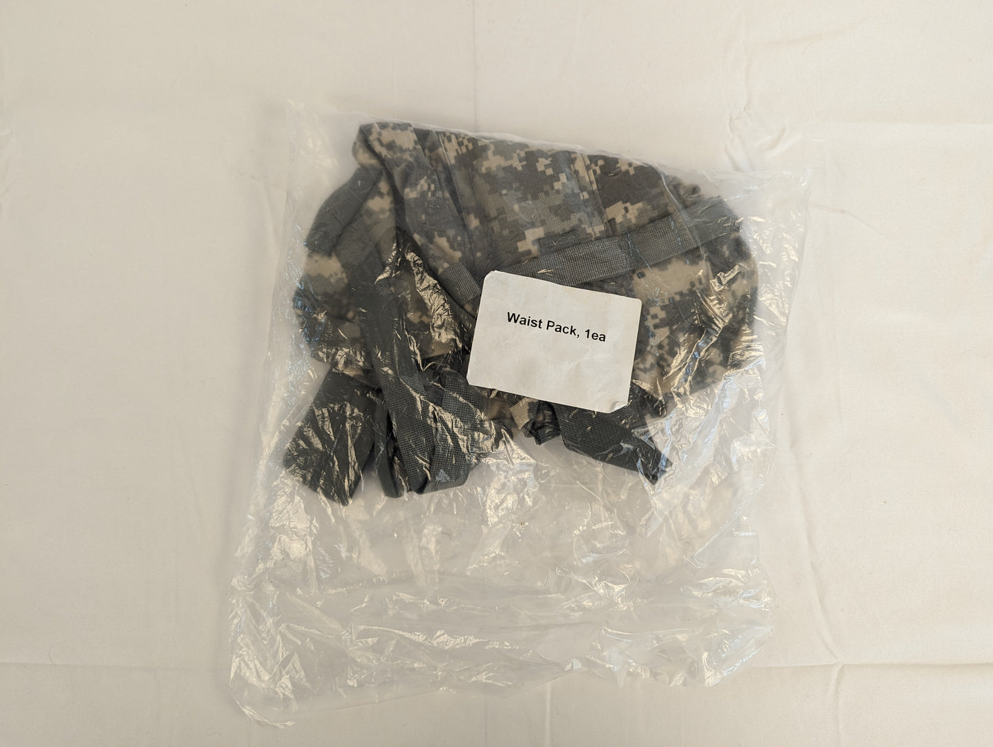A new U.S. Military Surplus Waist Pack in ACU digital camouflage, sealed inside clear plastic packaging, featuring a prominent label reading 'Waist Pack, 1ea'.