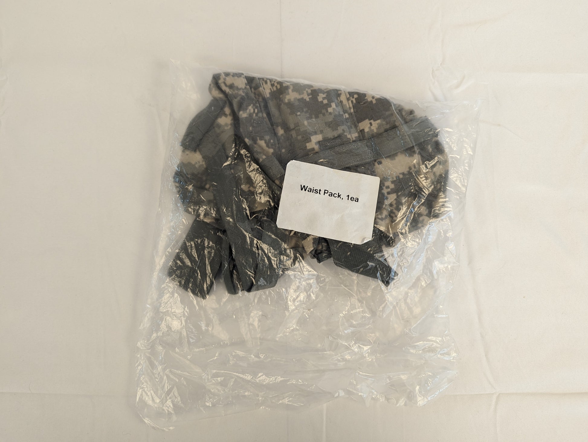 A new U.S. Military Surplus Waist Pack in ACU digital camouflage, sealed inside clear plastic packaging, featuring a prominent label reading 'Waist Pack, 1ea'.