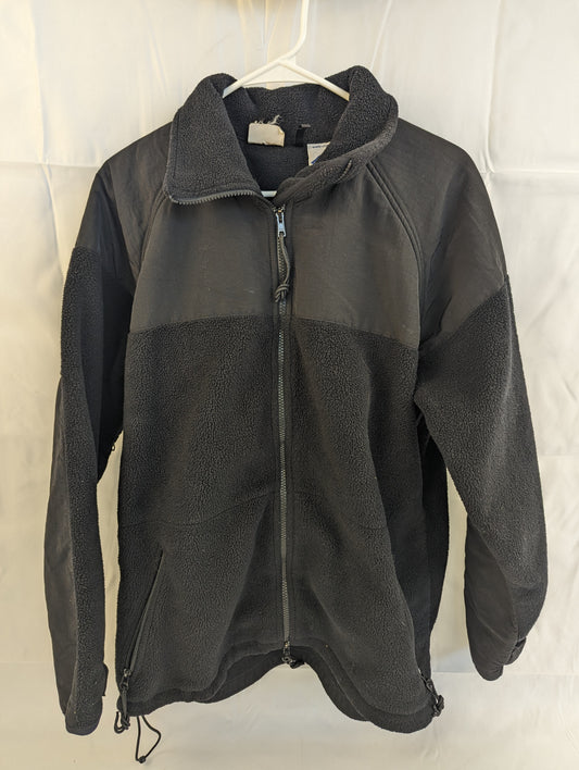 A front view of a black U.S. Military Cold Weather Fleece Jacket hanging on a hanger, featuring reinforced nylon shoulder and chest panels, a full-length zipper, and two lower pockets.