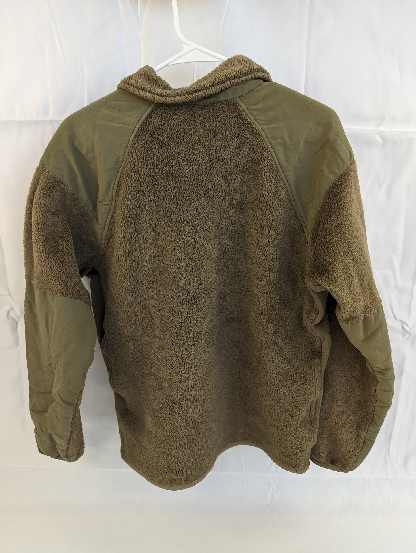 A back view of a U.S. Military Cold Weather Fleece Jacket in Coyote Brown hanging on a hanger, featuring reinforced nylon panels across the shoulders, elbows, and the upper back yoke.