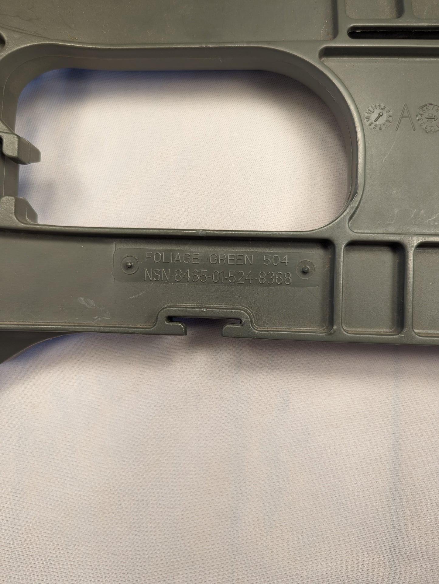 A close-up photograph of the olive green plastic frame of a U.S. Military Enhanced Rucksack Frame, clearly displaying the embossed text 'PAT. PEND.' and the National Stock Number (NSN) 8465-01-519-8389.