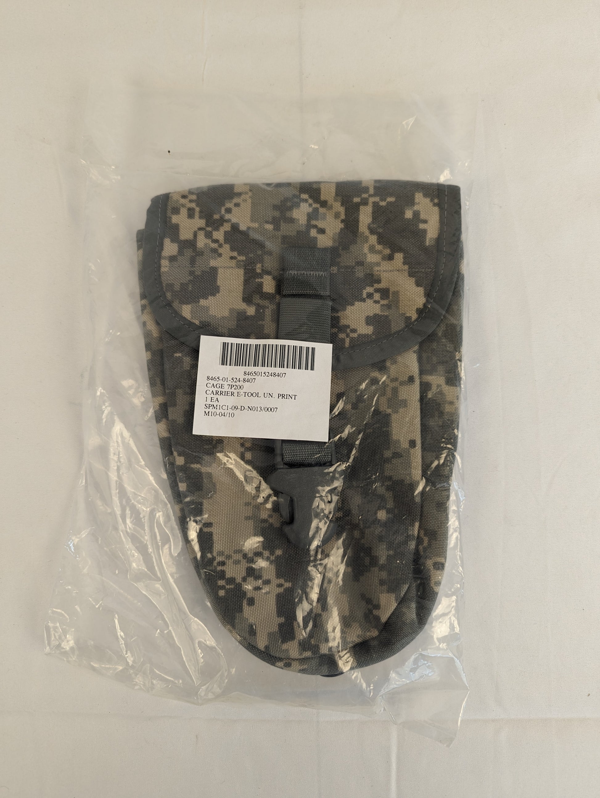 A new U.S. Military Surplus Entrenching Tool Carrier pouch in ACU digital camouflage, sealed in clear plastic, displaying its rounded, tapered shape and original issue label.