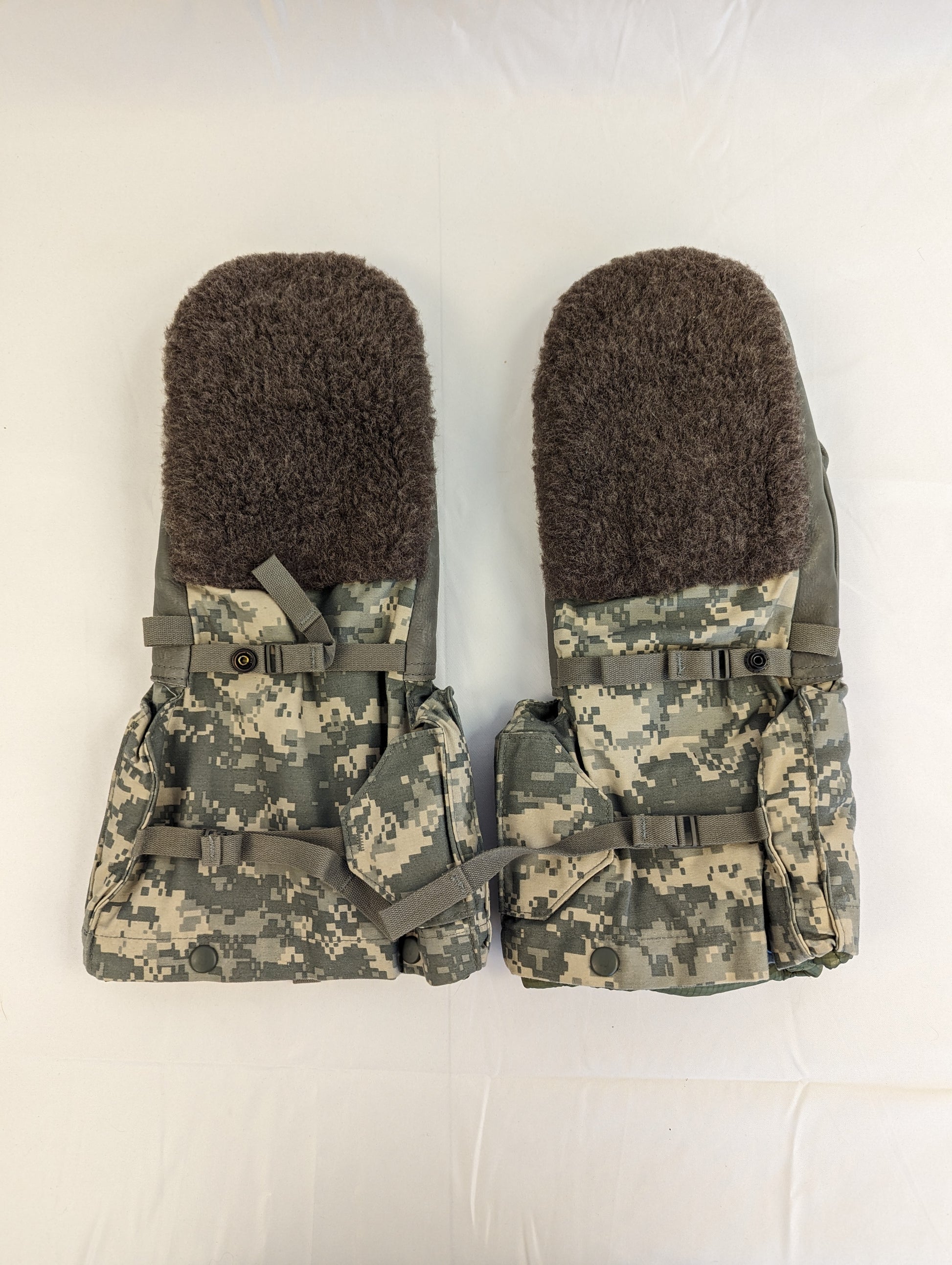 A pair of U.S. Military Extreme Cold Weather Mittens laid flat, featuring a dark olive suede palm and back with ACU digital camouflage cuffs and thick fur lining visible.