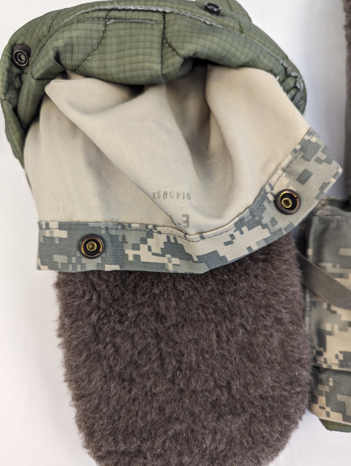 A close-up view looking into the open cuff of a U.S. Military Extreme Cold Weather Mitten, showing the thick, dark fur lining, the ACU digital camouflage outer cuff, and the inner knit wristlet.