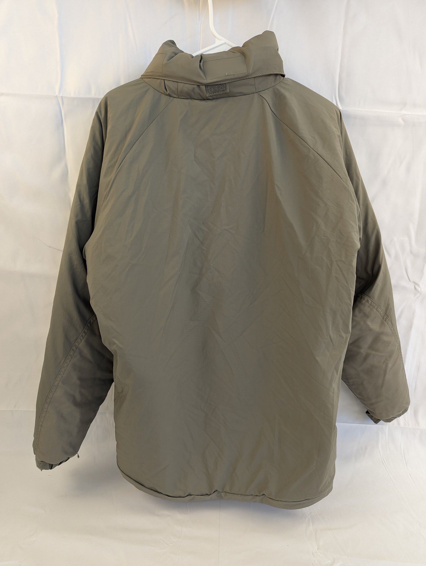 A back view of a U.S. Military Extreme Cold Weather Parka in gray/foliage green, hanging on a white hanger, highlighting the bulky, quilted insulation and high collar.