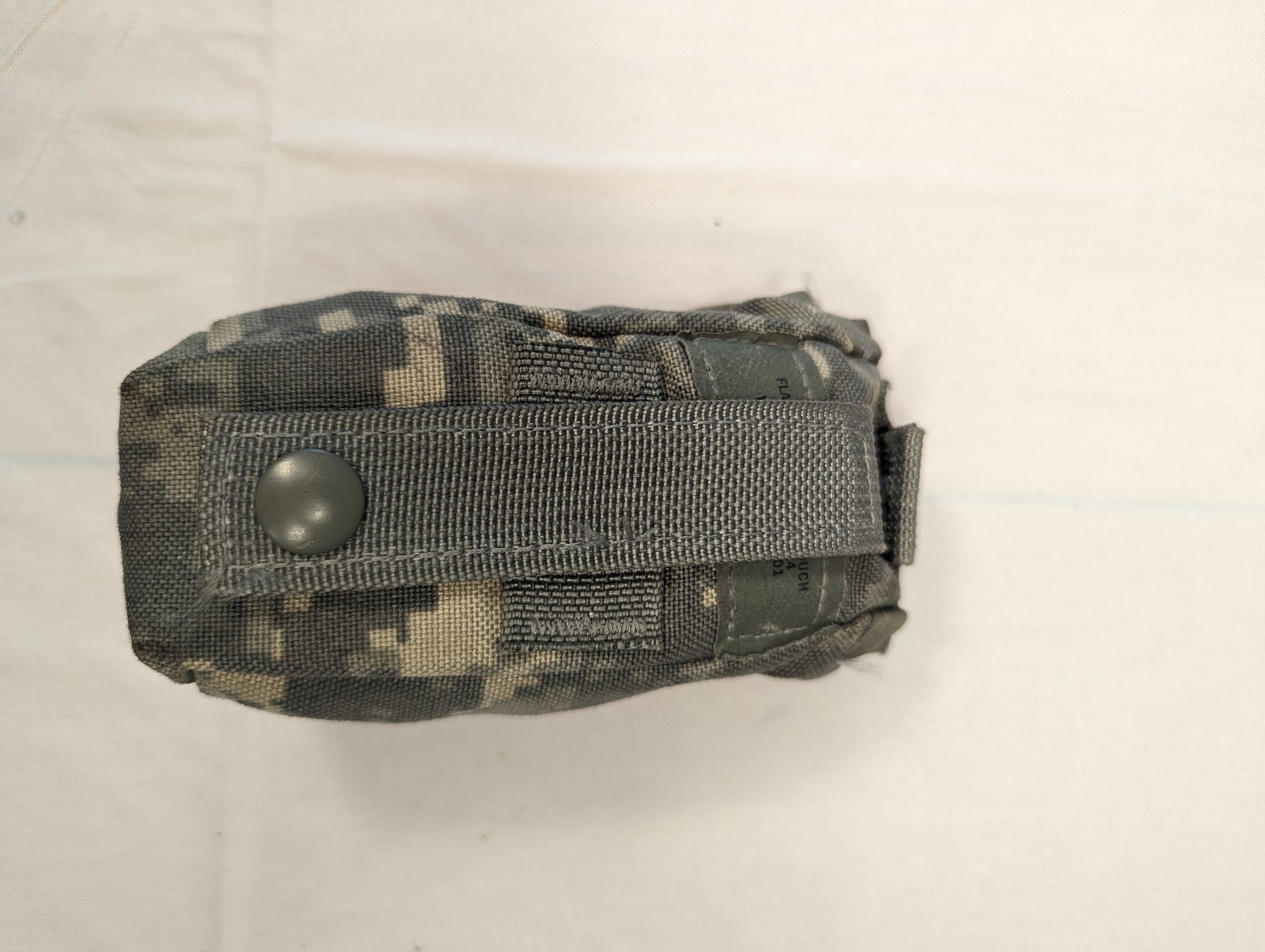 A single U.S. Military Surplus small pouch in ACU digital camouflage, laid flat, secured by a large horizontal gray webbing strap with a black snap button closure, and featuring MOLLE webbing loops.