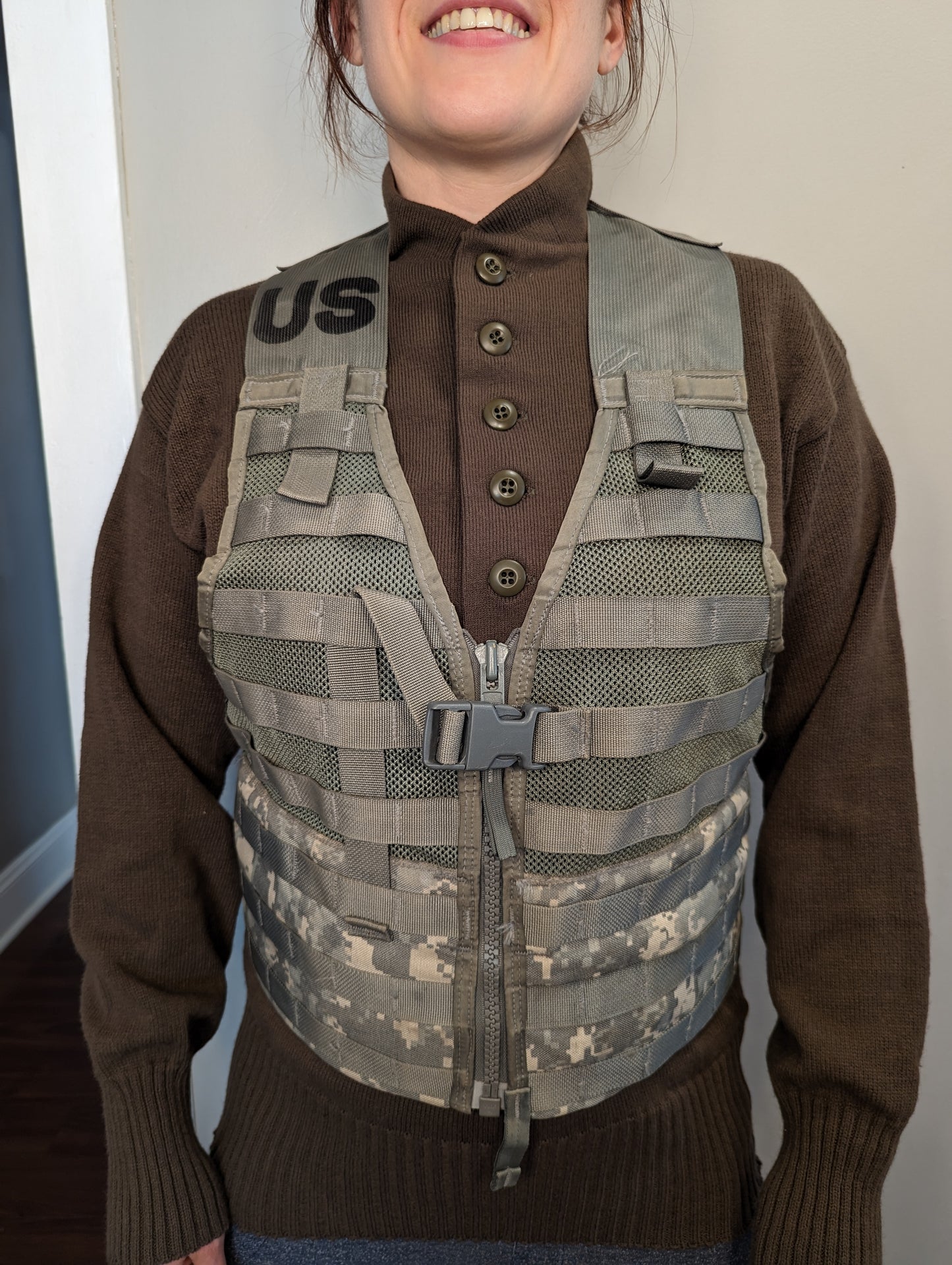 A person wearing a U.S. Military Surplus Fighting Load Carrier (FLC) Vest in ACU digital camouflage, highlighting the fit, MOLLE webbing, front buckle, and the prominent stenciled 'US' mark.