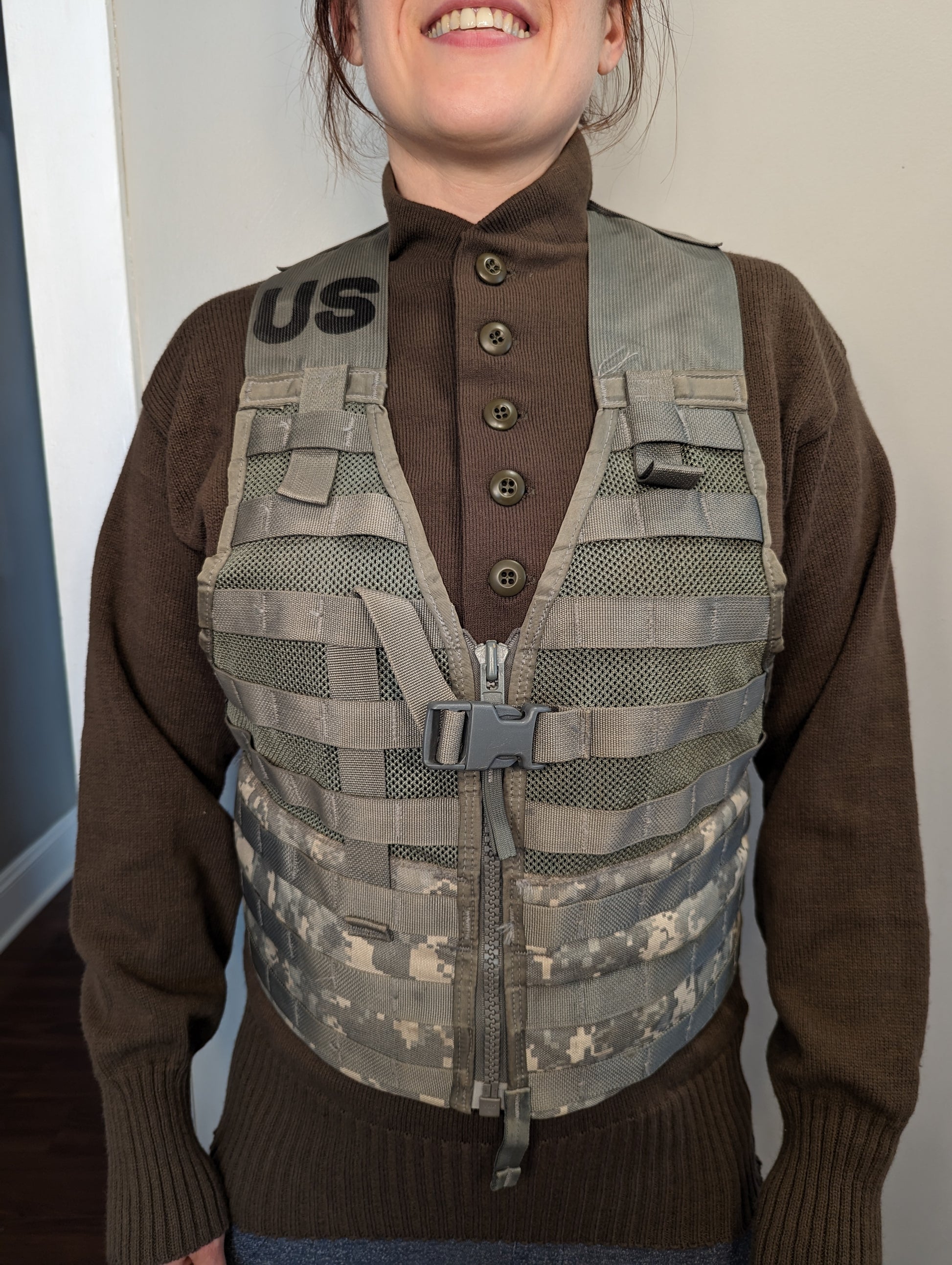 A person wearing a U.S. Military Surplus Fighting Load Carrier (FLC) Vest in ACU digital camouflage, highlighting the fit, MOLLE webbing, front buckle, and the prominent stenciled 'US' mark.