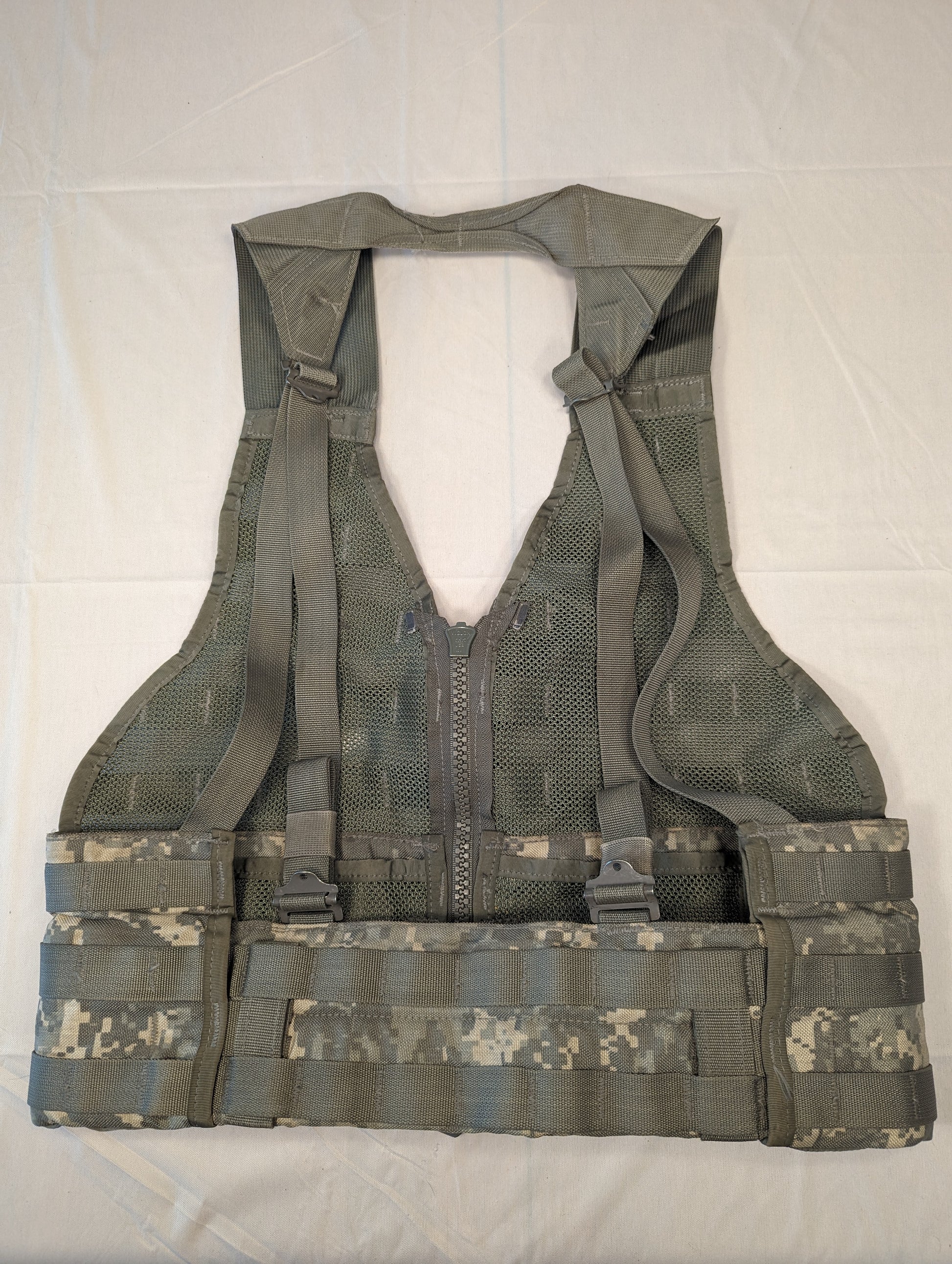 A full rear view of a U.S. Military Surplus Fighting Load Carrier (FLC) Vest in ACU/UCP camouflage, laid flat, highlighting the deep V-neck design, complex woven texture, and wide cummerbund area.