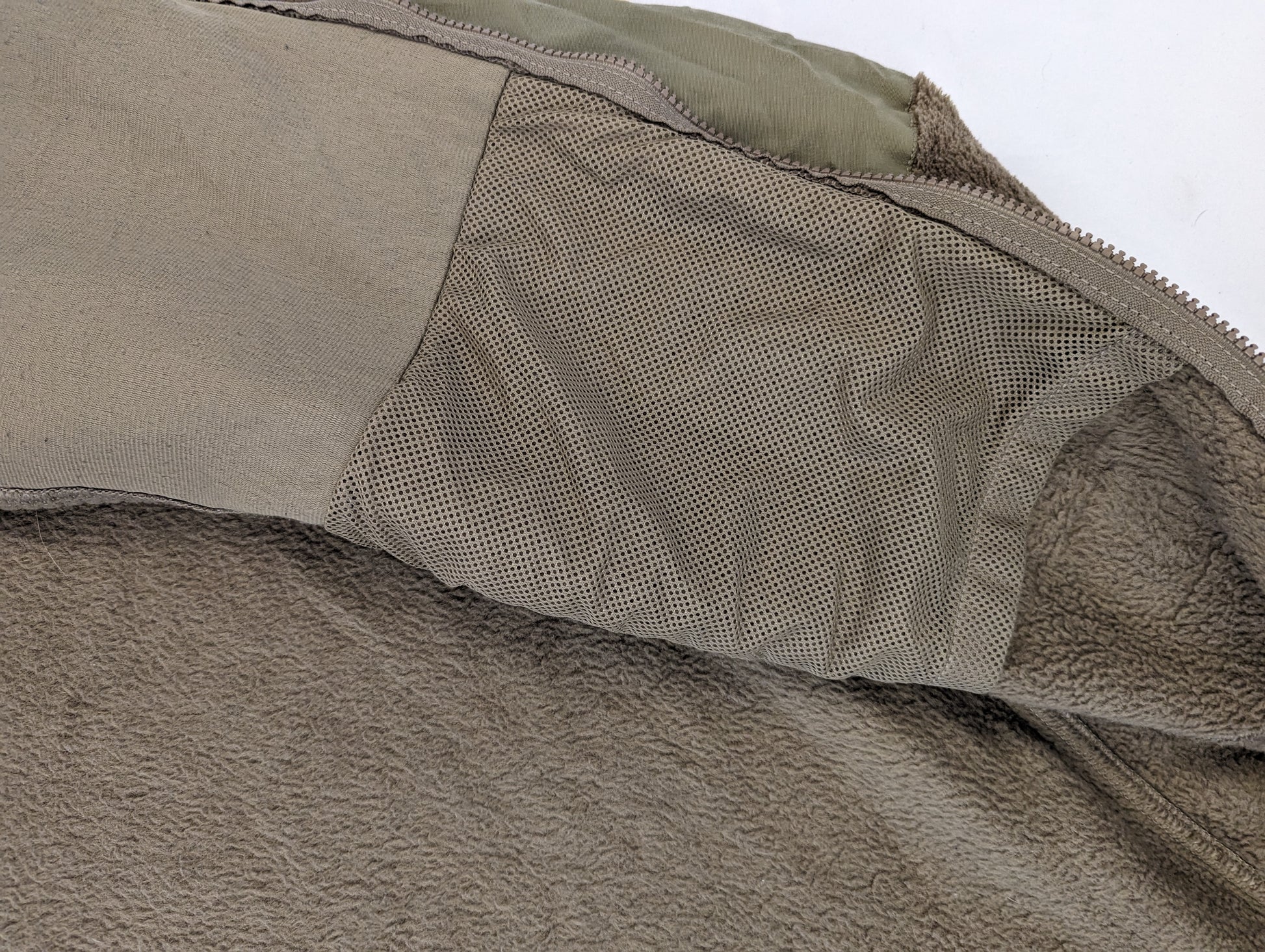 An extreme close-up detail shot of the Coyote Brown fleece jacket, highlighting the contrast between the fuzzy fleece texture and the smoother, reinforced zipper placket fabric.