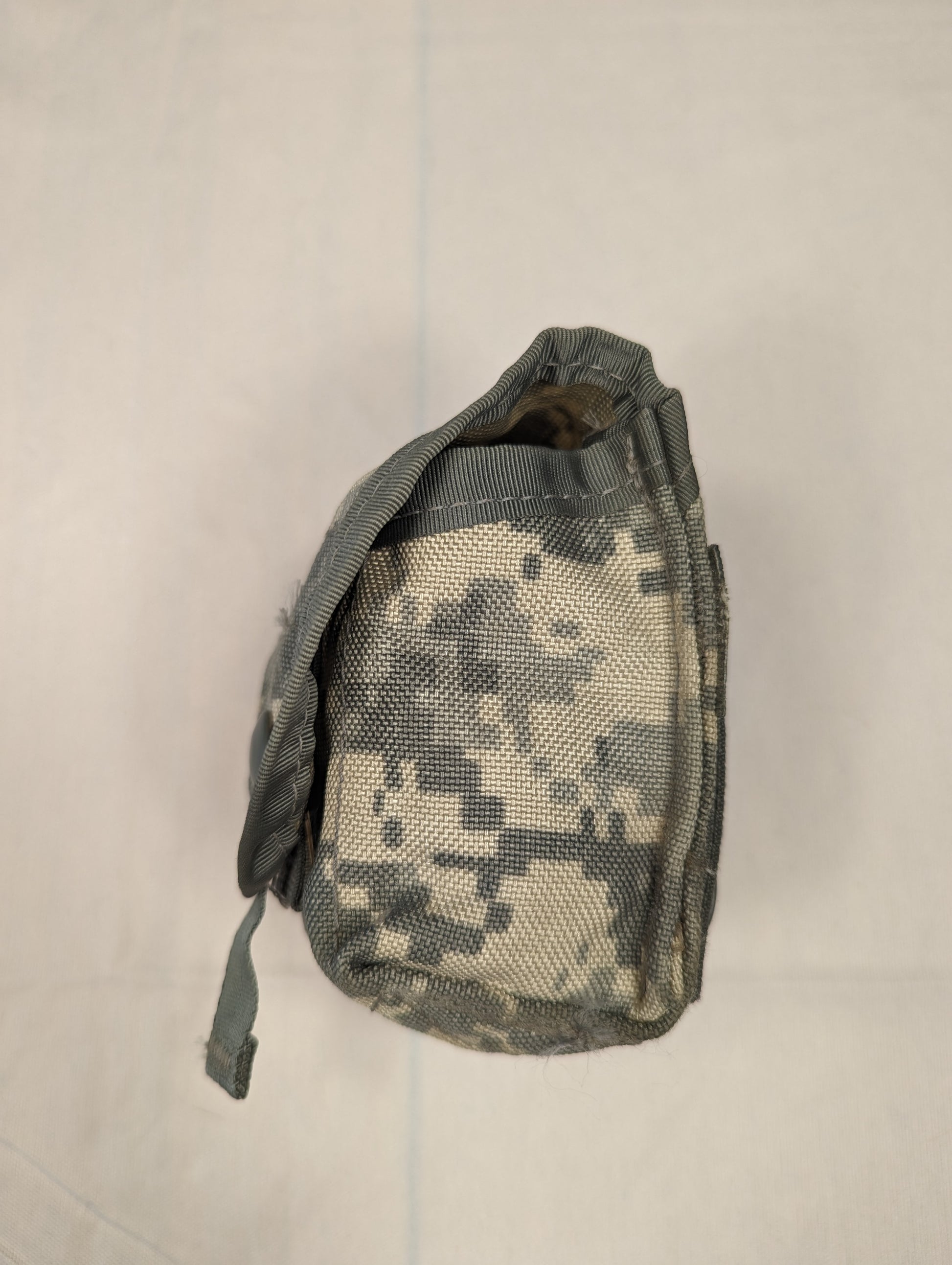 A side profile view of a single U.S. Military Surplus Hand Grenade Pouch in ACU digital camouflage, highlighting the flap closure and the pouch's depth.
