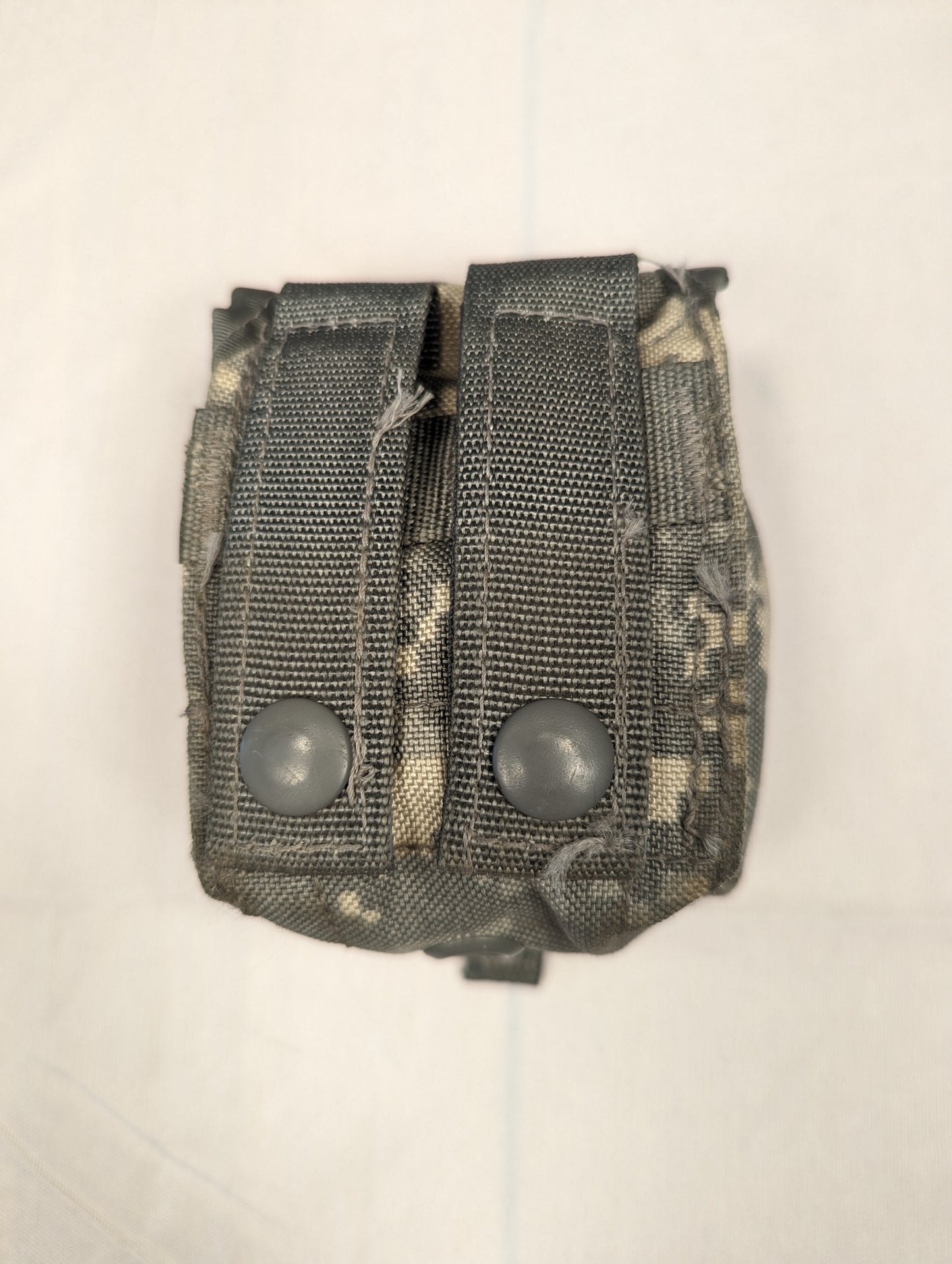 A single U.S. Military Surplus Hand Grenade Pouch in ACU digital camouflage, photographed from the back to show the two vertical MOLLE attachment straps and metal snap buttons.