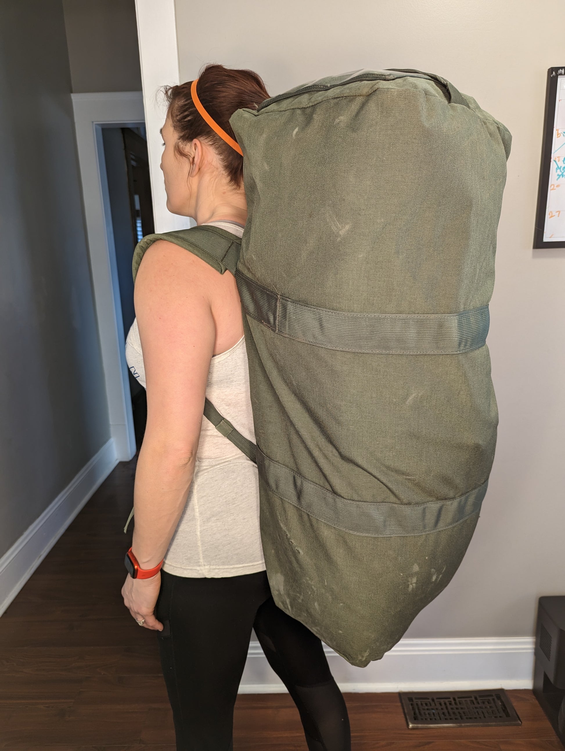 A large U.S. Military Surplus Improved Duffel Bag (IDB) in olive green, standing upright, featuring heavy-duty webbing and compression straps