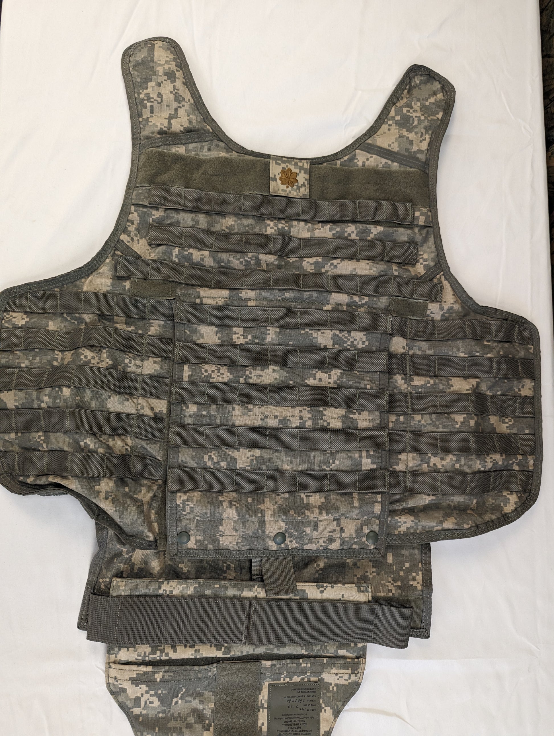 A large Improved Outer Tactical Vest (IOTV) in ACU digital camouflage, displayed flat on its back, highlighting the drag handle, rear plate pocket, and adjustable shoulder panels.