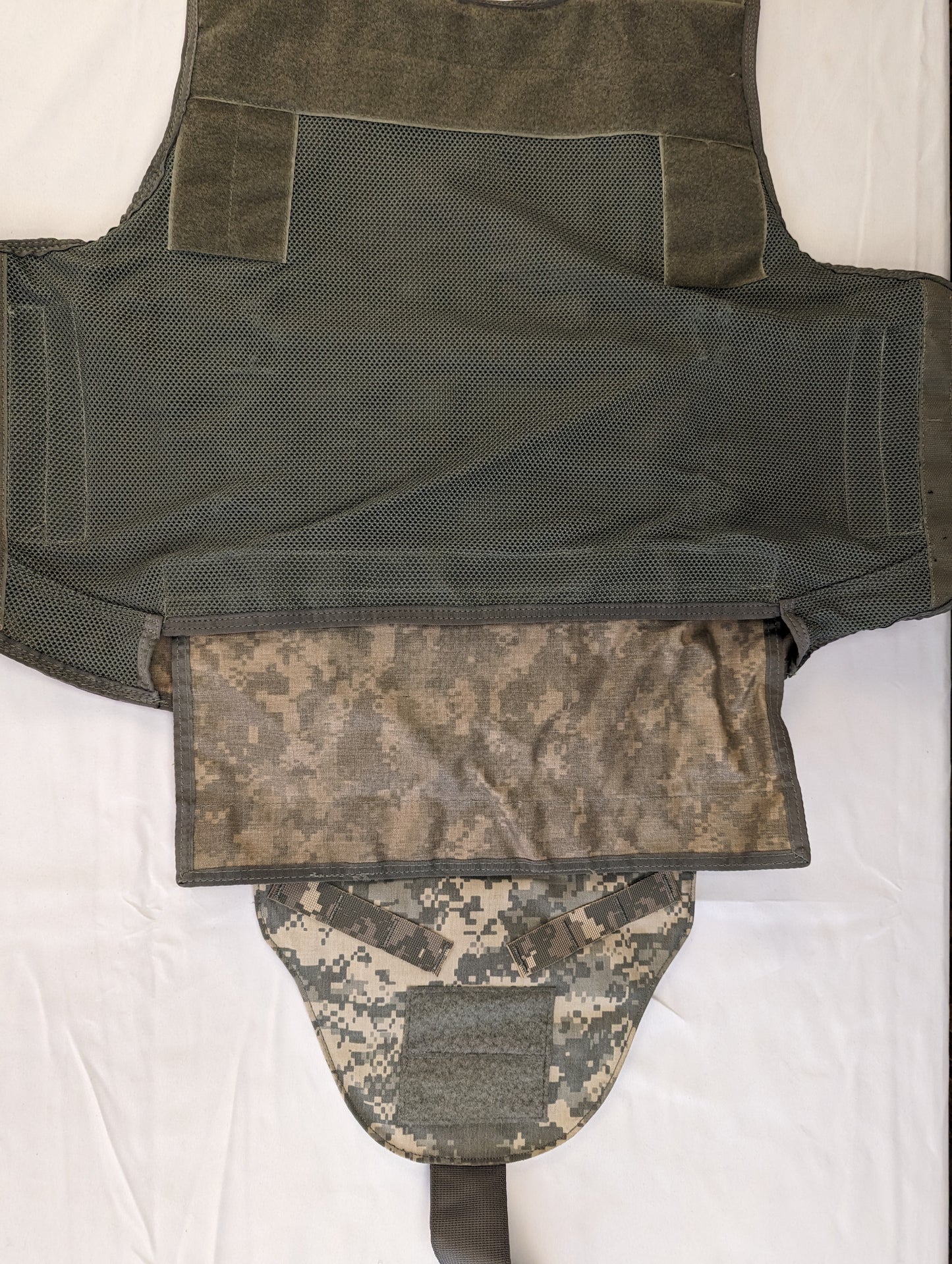 A close-up of the internal, mesh side panels and cummerbund of the Improved Outer Tactical Vest (IOTV), showing the hook-and-loop closure system laid flat.