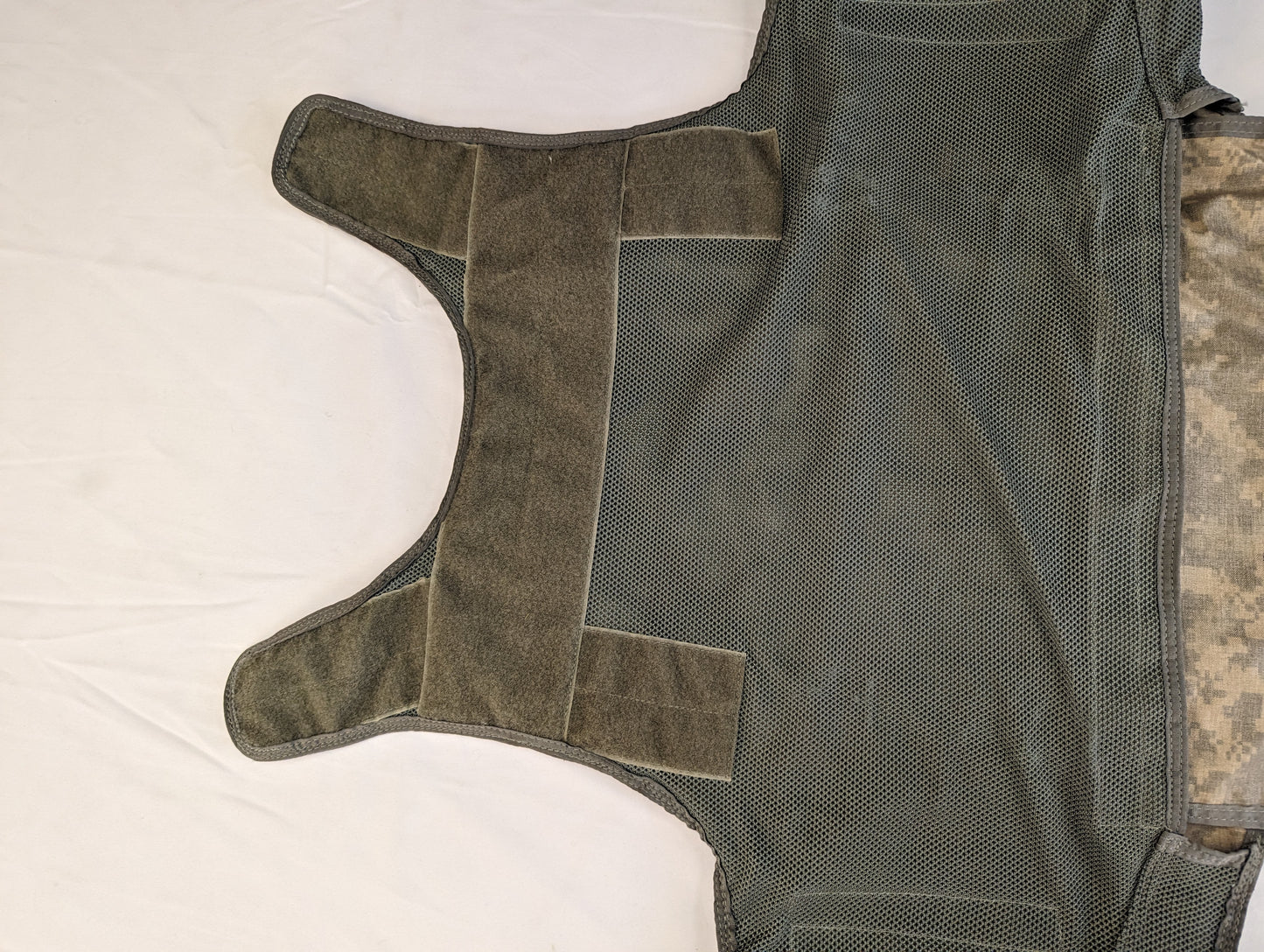 A close-up of the internal, mesh side panels of the Improved Outer Tactical Vest (IOTV), showing the hook-and-loop cummerbund closure system laid flat.