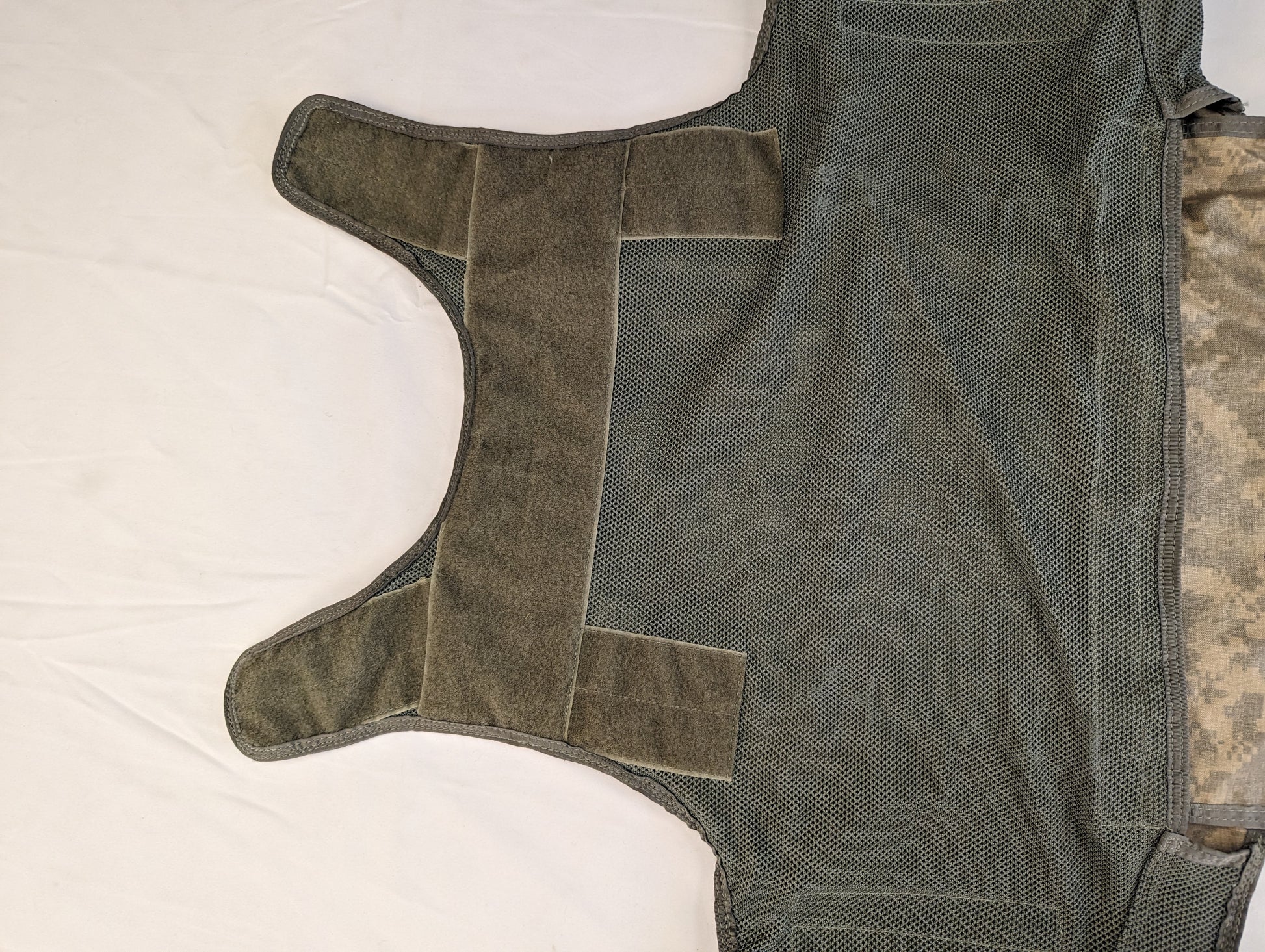 A close-up of the internal, mesh side panels of the Improved Outer Tactical Vest (IOTV), showing the hook-and-loop cummerbund closure system laid flat.