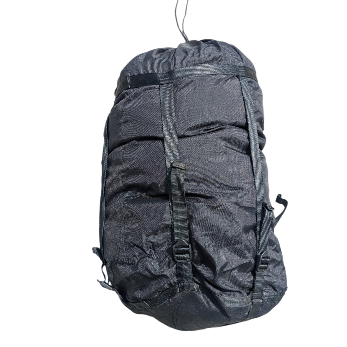 A large, tightly compressed U.S. Military Surplus Compression Stuff Sack in black, featuring heavy-duty webbing straps and buckles, isolated on a white background.