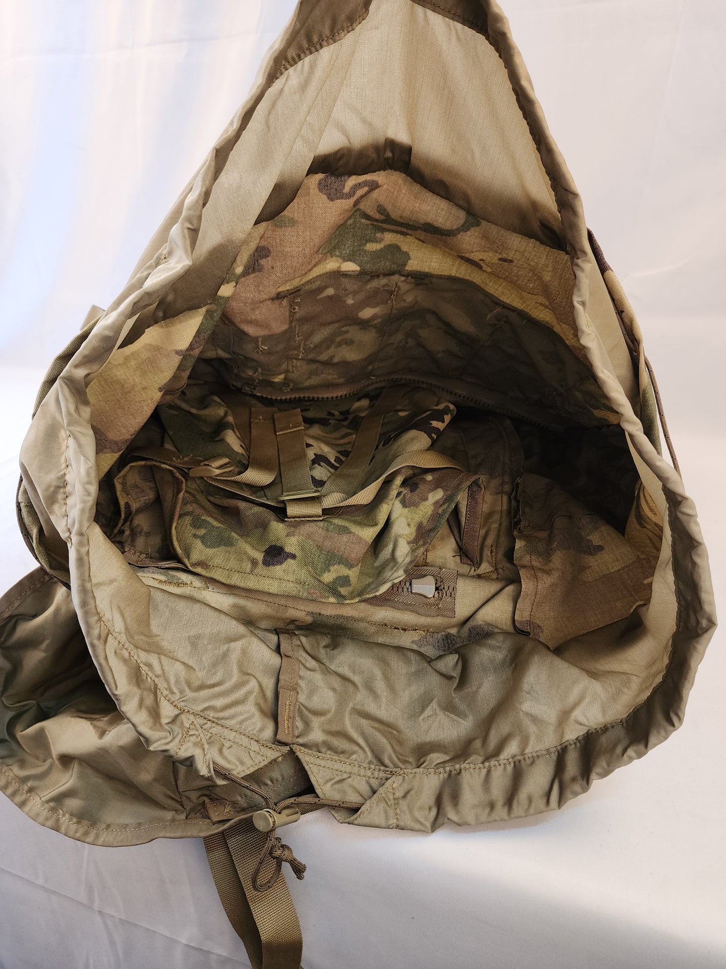 A close-up view looking down into the open main compartment of the OCP/Multicam MOLLE 4000 Rucksack, showing the cinched collar and the camouflage fabric interior.