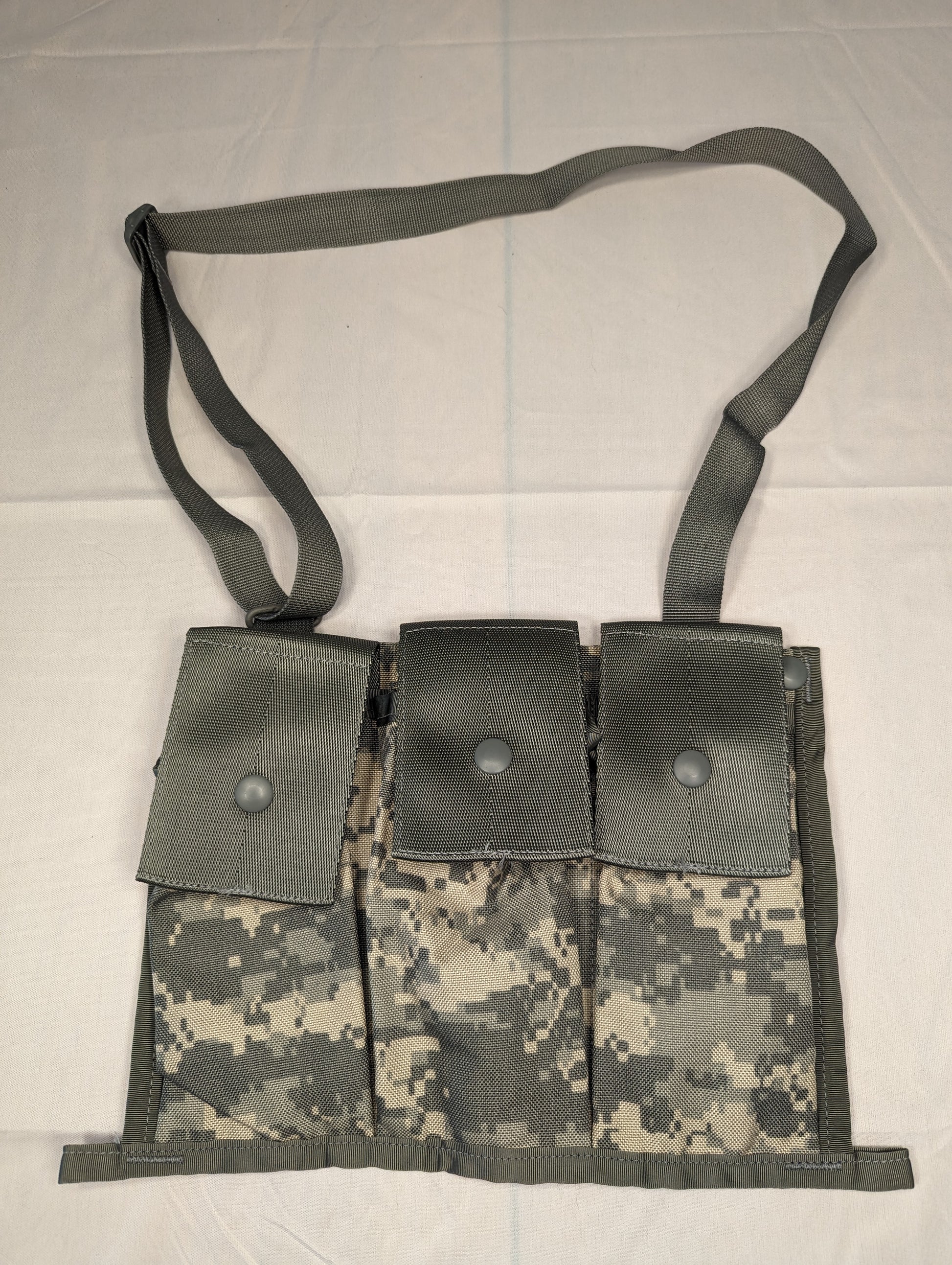A U.S. Military Surplus MOLLE II Bandoleer in ACU digital camouflage, laid flat, featuring three vertical magazine pouches with snap closures and an attached adjustable shoulder strap.