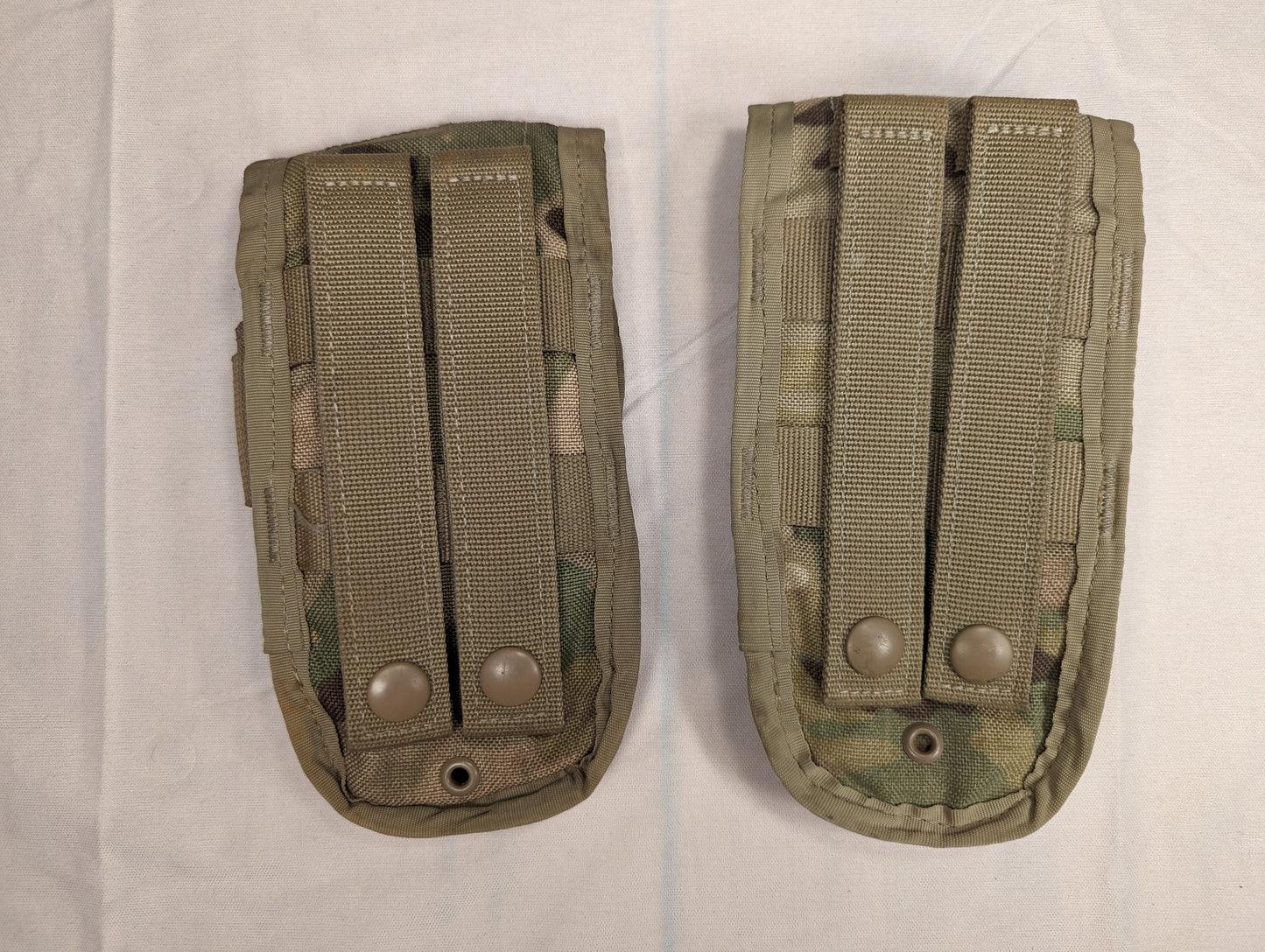 A back view of two U.S. Military Surplus MOLLE II Double Magazine Pouches in OCP/Multicam camouflage, showing the vertical MOLLE attachment straps and metal snap buttons.