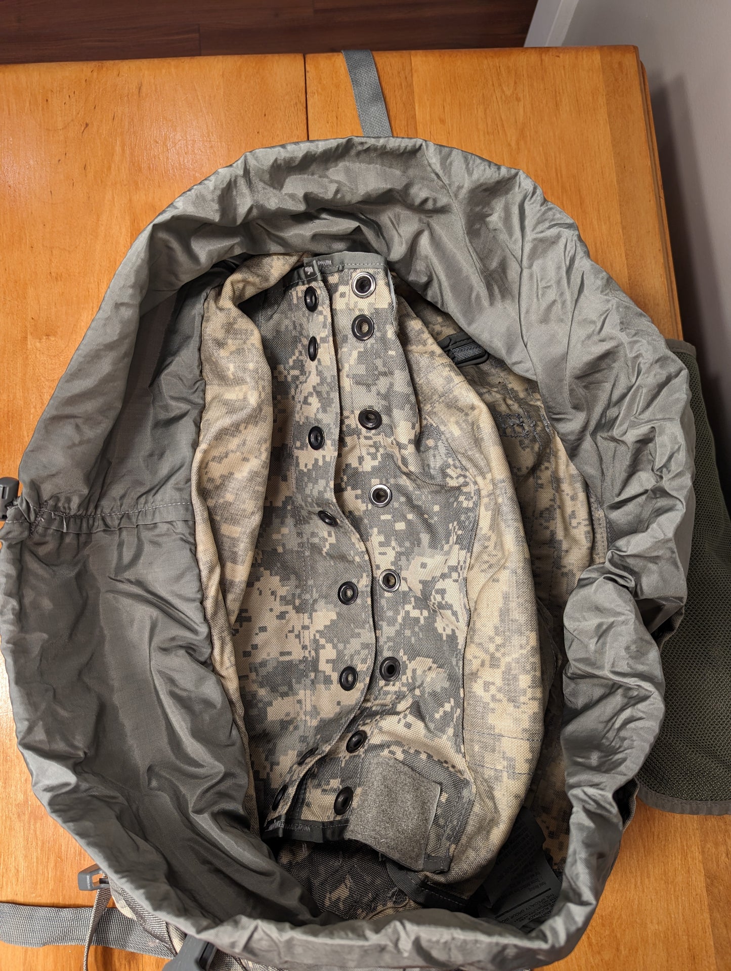 A top-down view looking into the open main compartment of a U.S. Military Surplus MOLLE II Large Rucksack in ACU digital camouflage, revealing the drawstring storm collar and the internal back panel with attachment hardware.