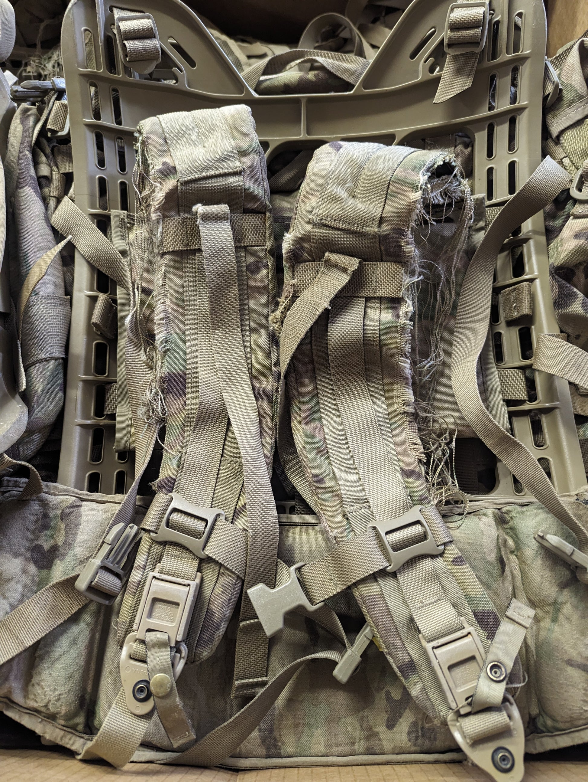 A close-up view of the back suspension system of a U.S. Military Large Field Pack in OCP/Multicam camouflage, highlighting the padded shoulder harness, quick-release buckles, and the rigid external frame.