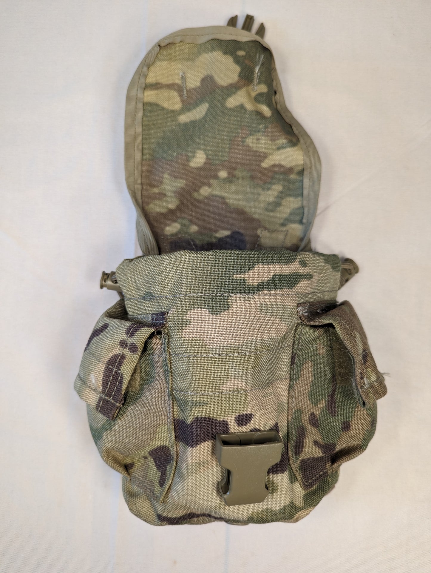 A U.S. Military Surplus Canteen/General Purpose Pouch in OCP/Multicam camouflage, standing upright, featuring a main body with two side pockets and a flap secured by a tan quick-release buckle.
