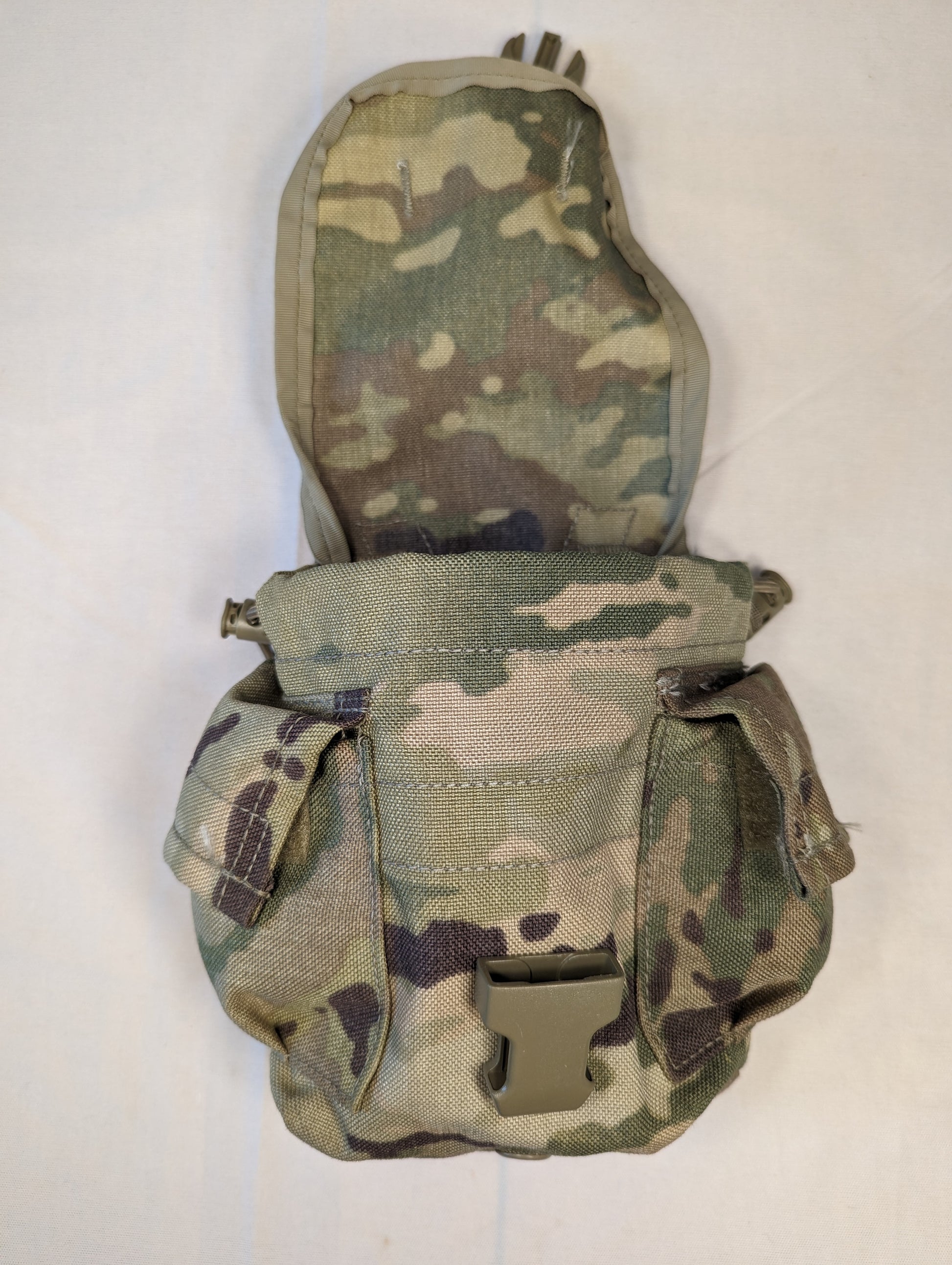 A U.S. Military Surplus Canteen/General Purpose Pouch in OCP/Multicam camouflage, standing upright, featuring a main body with two side pockets and a flap secured by a tan quick-release buckle.