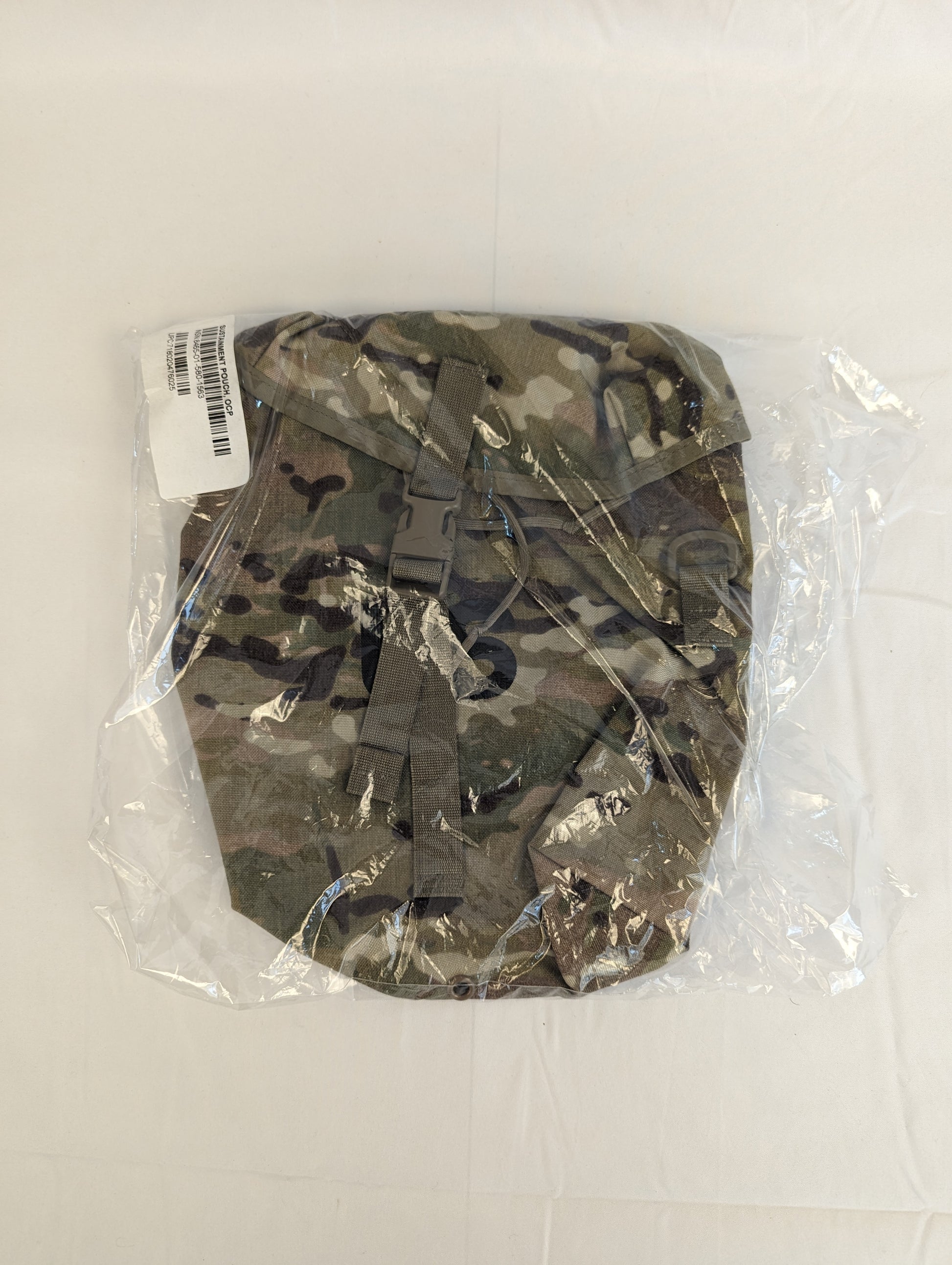 A front view of a U.S. Military Surplus Sustainment Pouch in OCP/Multicam camouflage, standing upright, featuring a buckle-secured top flap, MOLLE webbing, and the large stenciled 'US' mark.