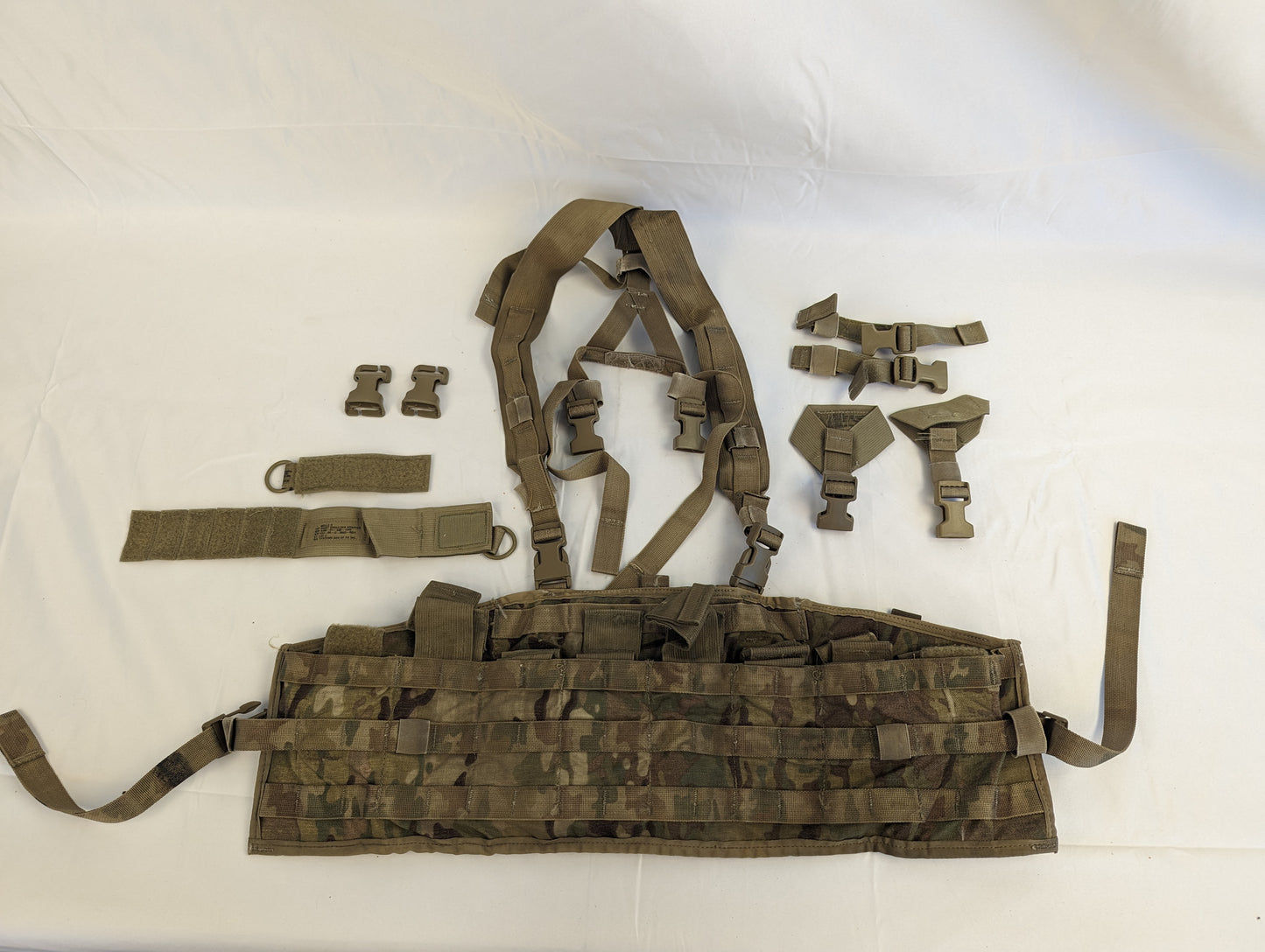 A complete U.S. Military Surplus Tactical Assault Panel (TAP) in OCP/Multicam camouflage, laid out flat in its disassembled state, showing the main panel, shoulder harness straps, and numerous quick-release plastic buckles.