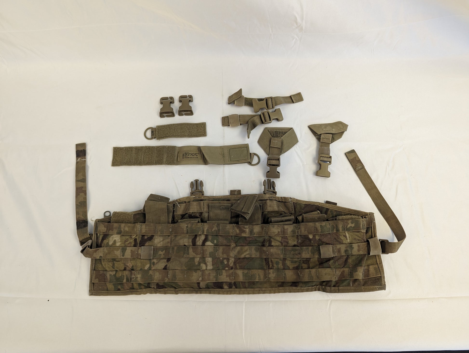 A complete U.S. Military Surplus Tactical Assault Panel (TAP) in OCP/Multicam camouflage, laid out flat, showing the main panel with MOLLE webbing and the detached adjustable shoulder harness system.