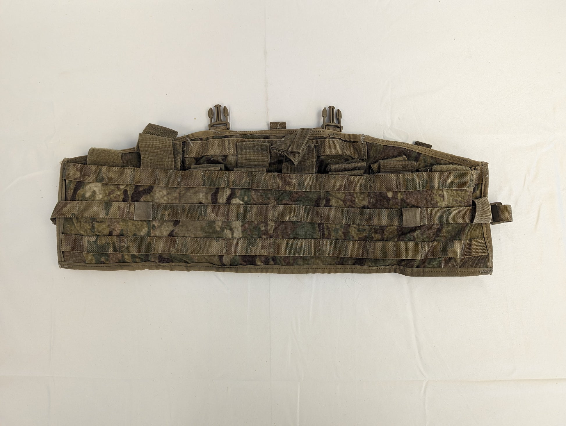 A U.S. Military Surplus Tactical Assault Panel or Chest Rig in OCP/Multicam camouflage, laid flat, featuring multiple segmented pockets secured by webbing straps and extensive horizontal MOLLE webbing.