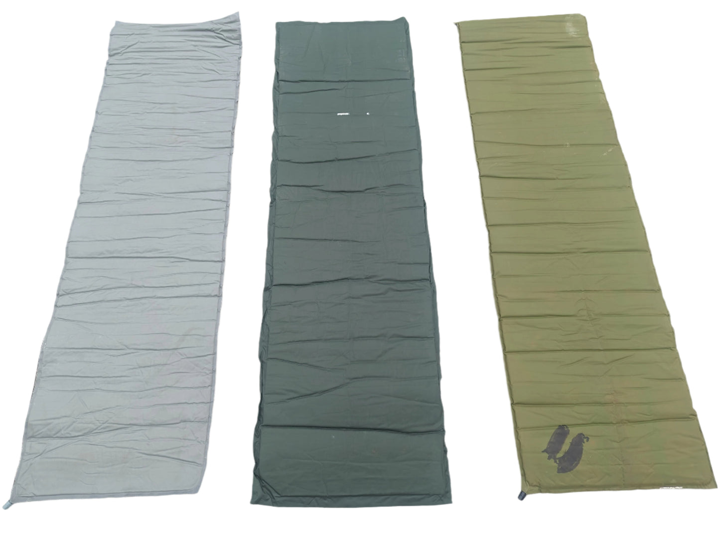 Three U.S. Military surplus self-inflating sleeping mats laid flat side-by-side on a white background, showing color variations in foliage green, dark gray, and olive drab.