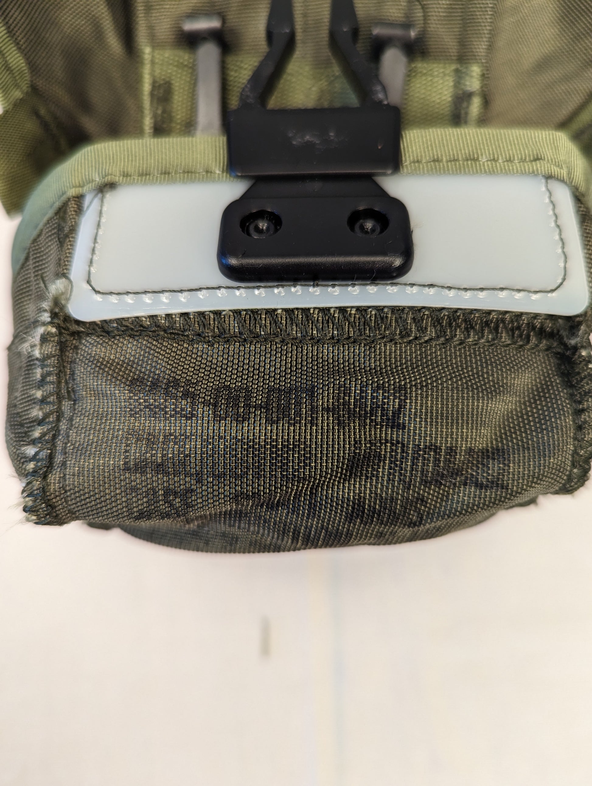 A close-up view of a U.S. Military Surplus Small Arms Ammunition Pouch in olive green, showing the black quick-release buckle closure and faintly stenciled 'U.S.' military marking on the fabric.