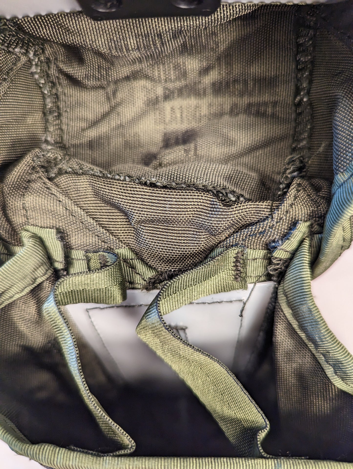 A close-up view of the empty interior of a U.S. Military Small Arms Ammunition Pouch in olive green, clearly displaying the three vertical webbing sleeves designed for internal magazine organization.