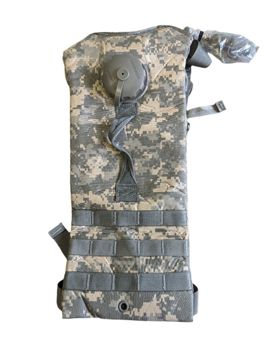 A front view of a U.S. Military Surplus Hydration Carrier in ACU digital camouflage, featuring a narrow profile, MOLLE webbing loops, and a drinking port visible at the top.