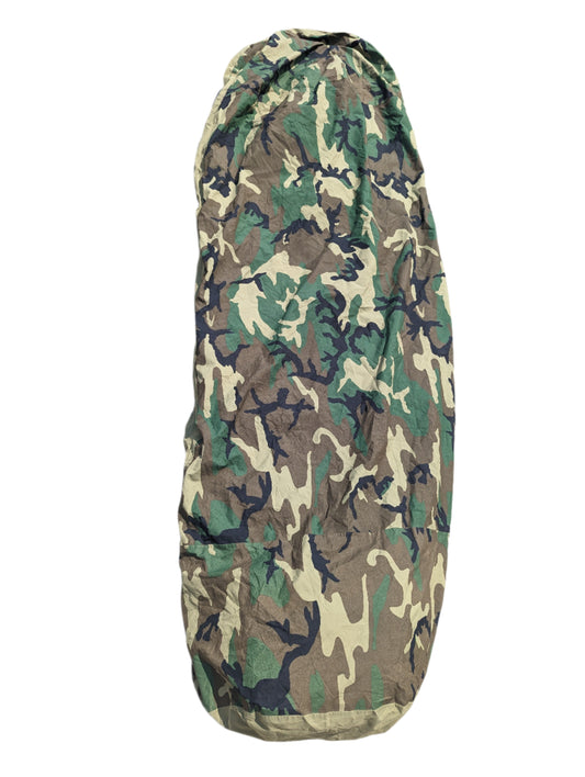 A full-length U.S. Military Surplus Bivy Cover in Woodland camouflage, zipped closed and isolated on a white background, displaying its wrinkled, mummy-shaped waterproof shell.