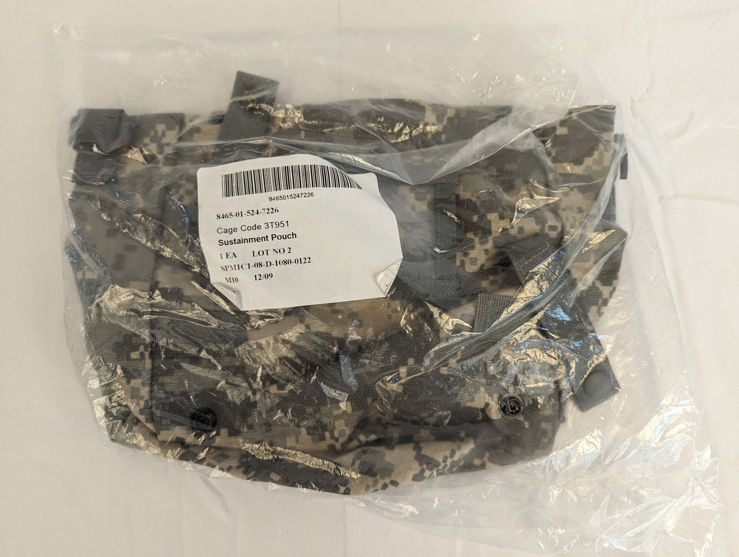 A new U.S. Military Surplus Sustainment Pouch in ACU digital camouflage, sealed inside clear plastic packaging, featuring the original issue label with product name, NSN, and contract details.