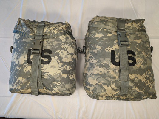 A studio shot of two U.S. Military Surplus Sustainment Pouches in ACU digital camouflage, standing upright side-by-side, featuring large stenciled 'US' markings and buckle-secured top flaps.
