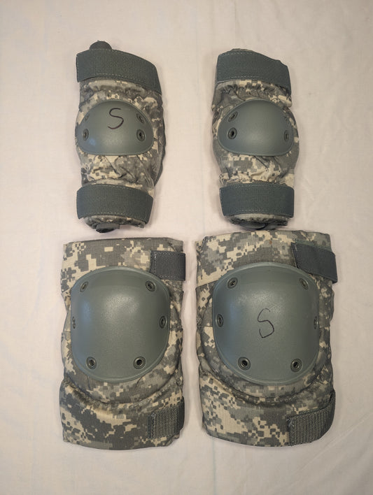 A set of four used U.S. Military tactical knee and elbow pads in ACU digital camouflage, laid out on a white background, featuring gray hard plastic shells and black size 'S' markings.